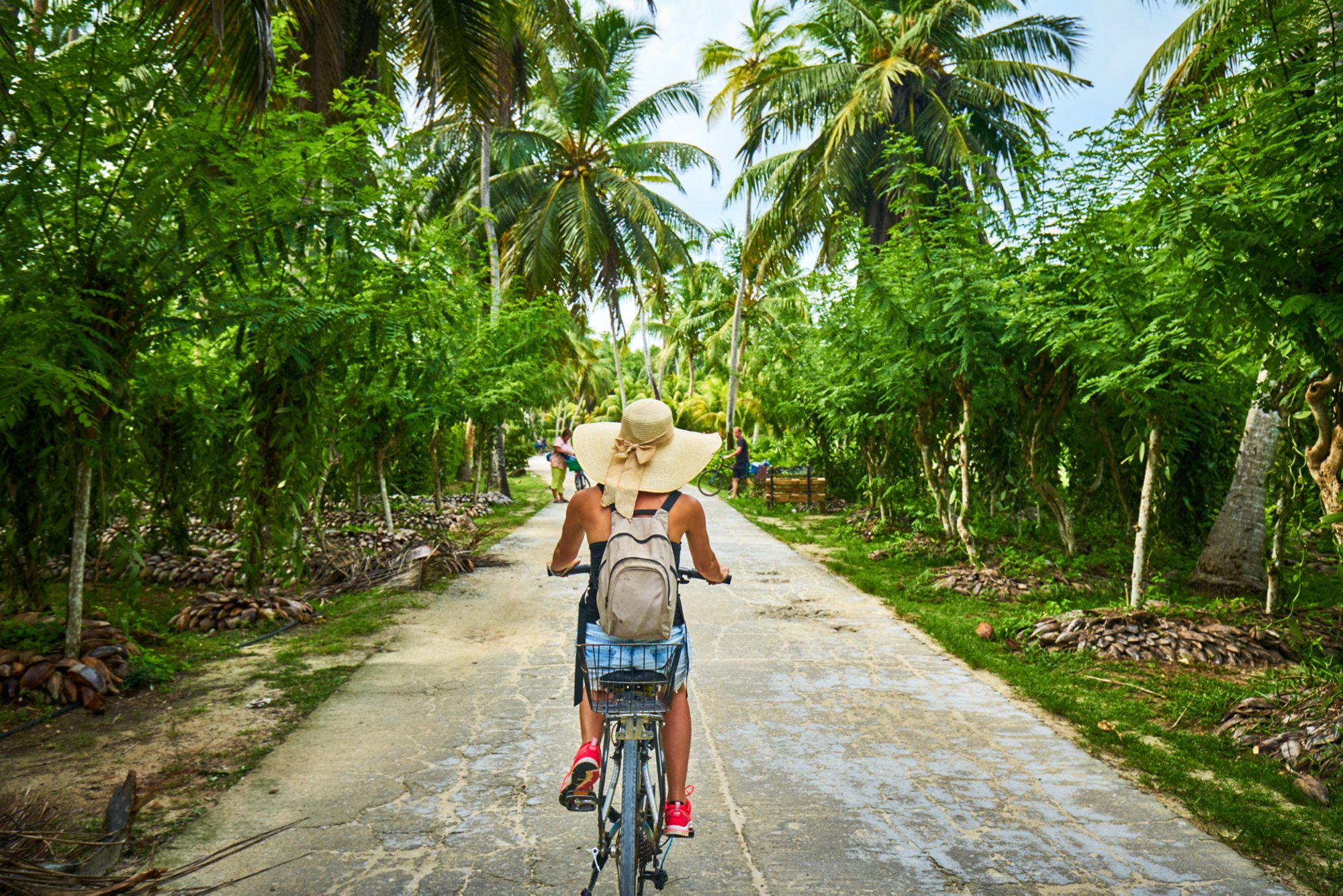 woman on a bicycle crosses vanilla plantations, dique island, seychelles