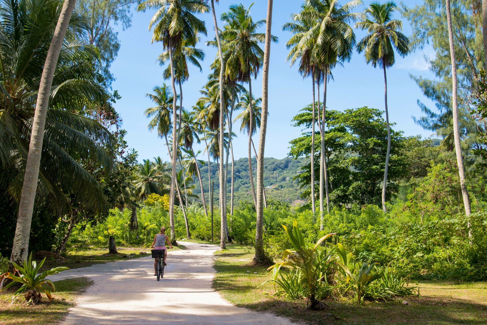 Woman bicycling on La Digue, Seychelles