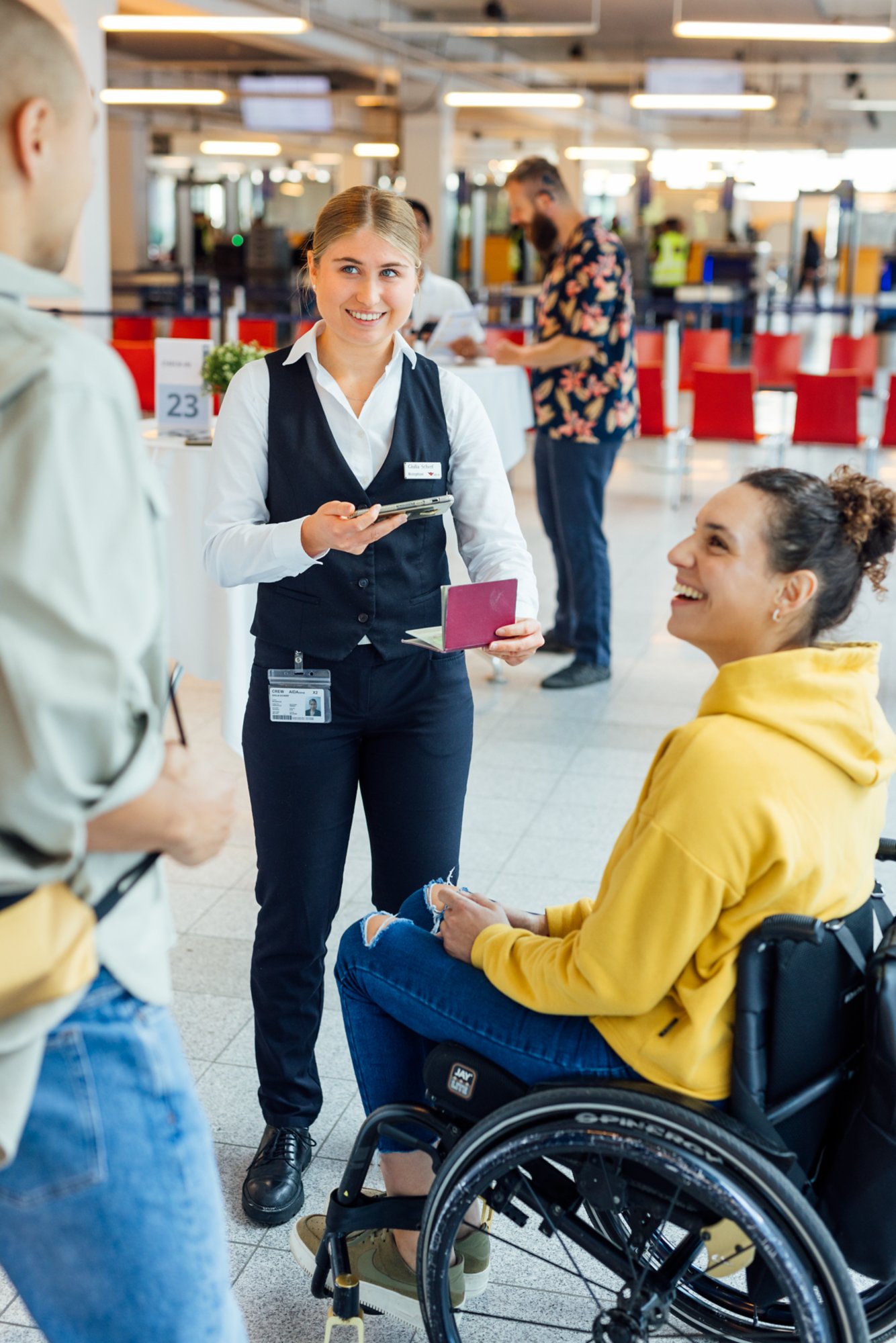 Frau im Rollstuhl checkt bei AIDA Mitarbeiterin ein