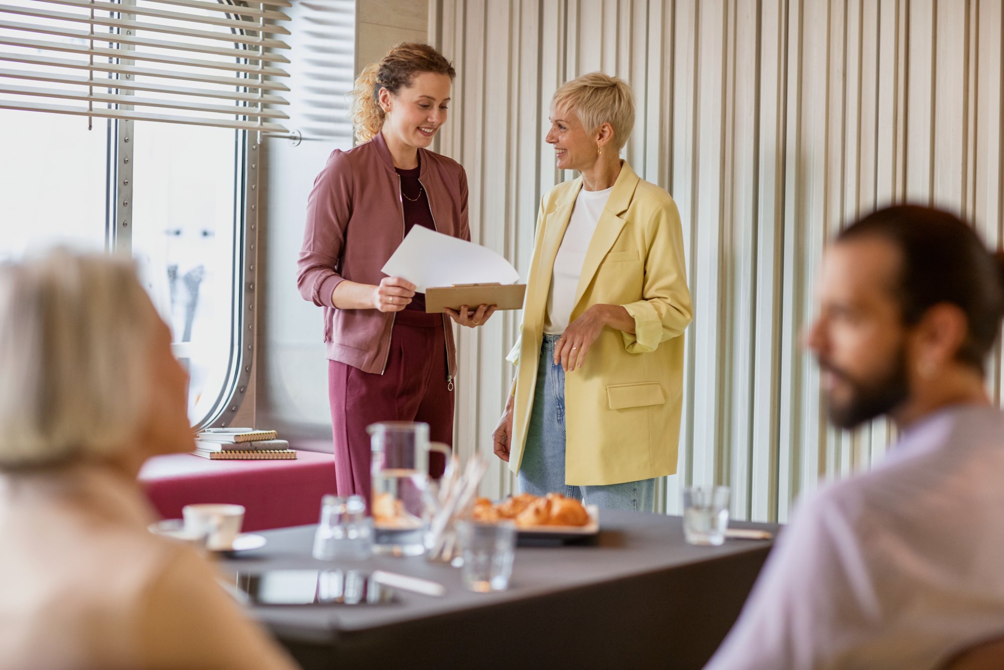 Zwei Frauen stehen vor Kolleg*innen und sprechen