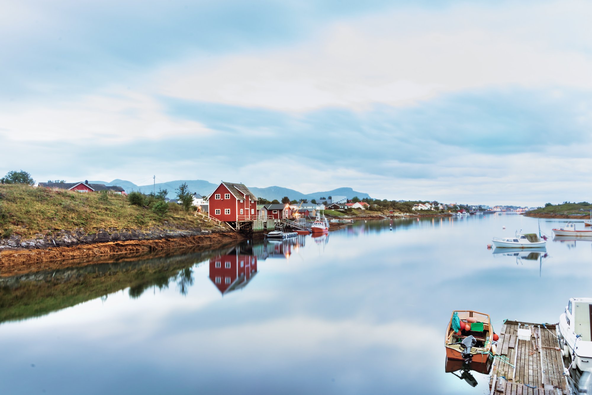 Blick auf einen kleinen Holzsteg und Holzhäuser neben dem Haupthafen von Bronnoysund in Norwegen.