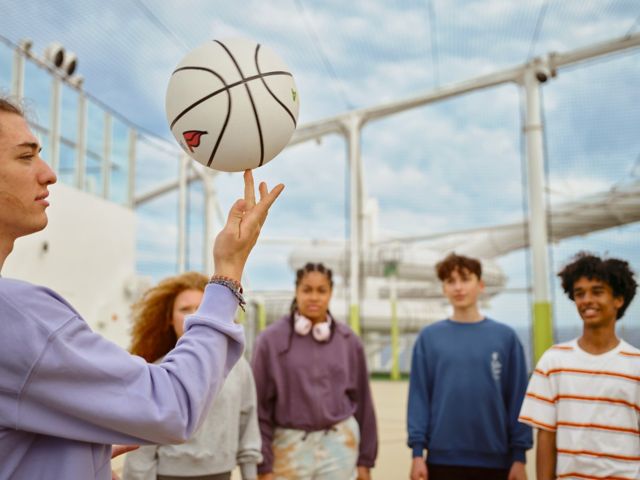 Eine Gruppe Jugendlicher auf dem Basketballplatz auf AIDA, ein Jugendlicher dreht einen Basketball auf einem Finger