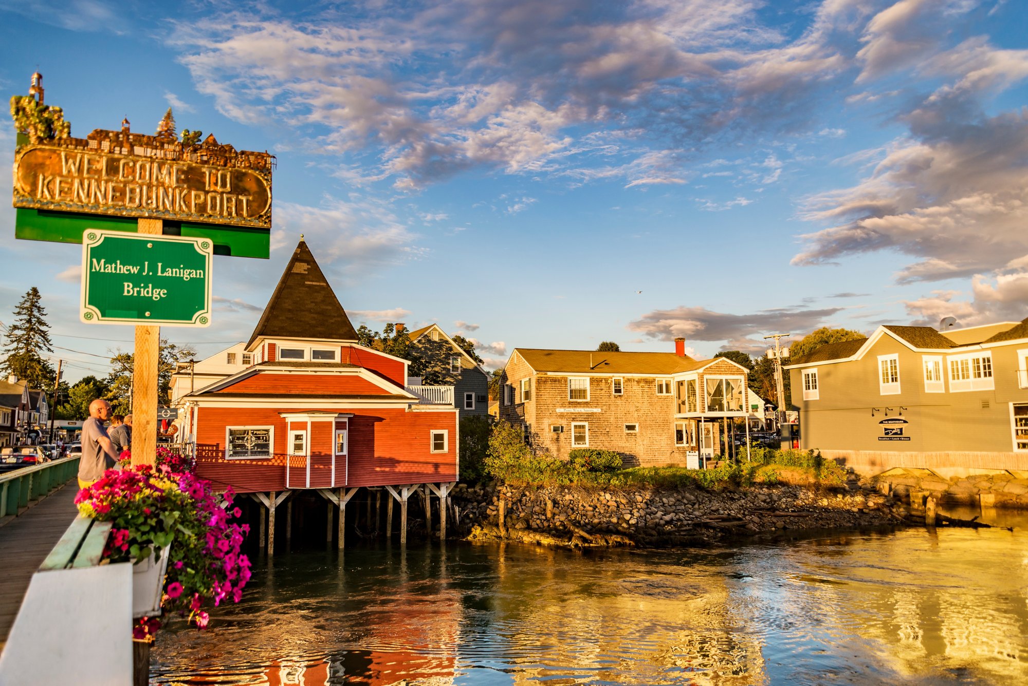 Ortseingang von Kennebunkport in Maine mit Holzhäusern am Wasser und blühenden Blumenkästen 