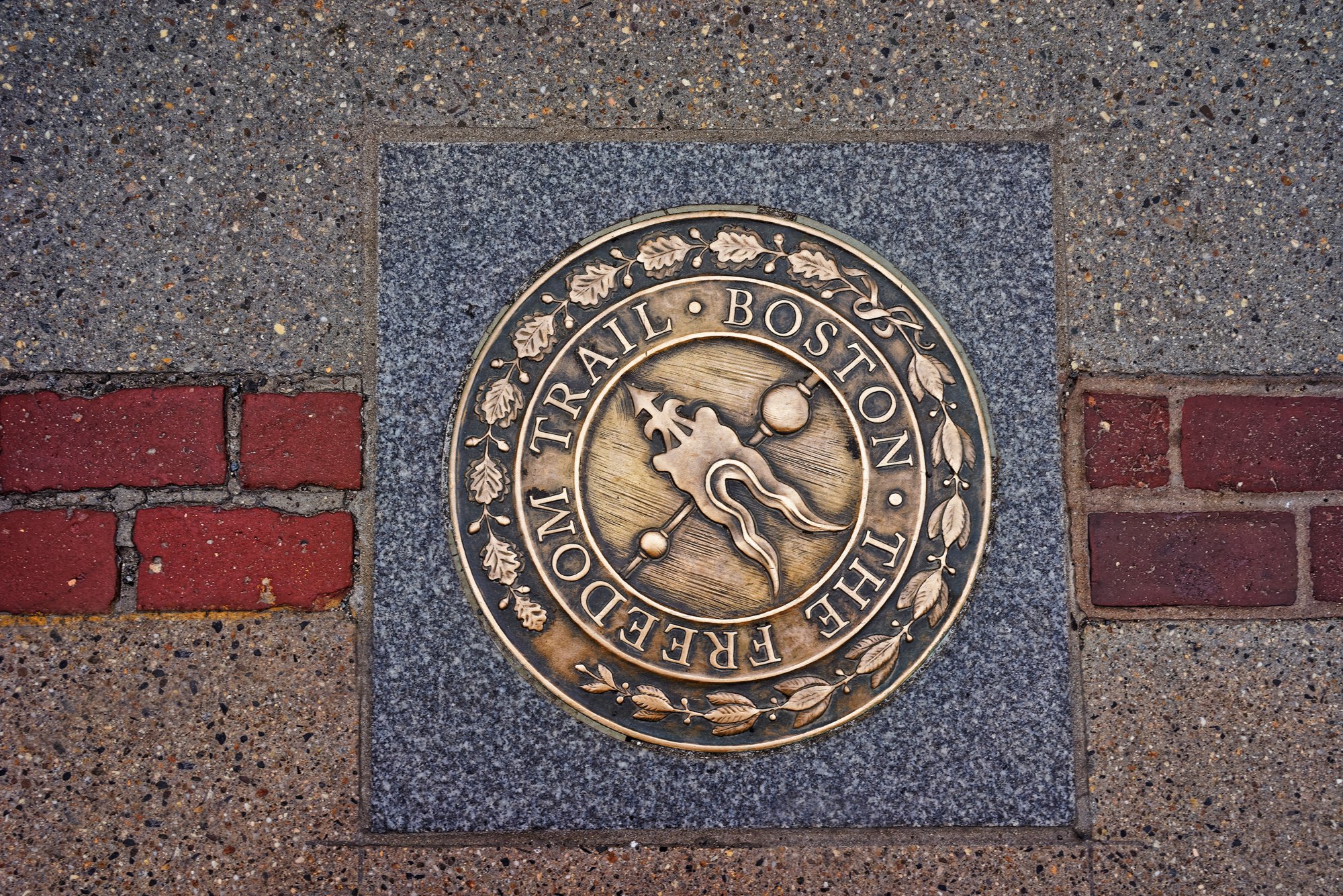 Bronzemedaillon des Freedom Trail im Pflaster von Boston zwischen roten Ziegeln 