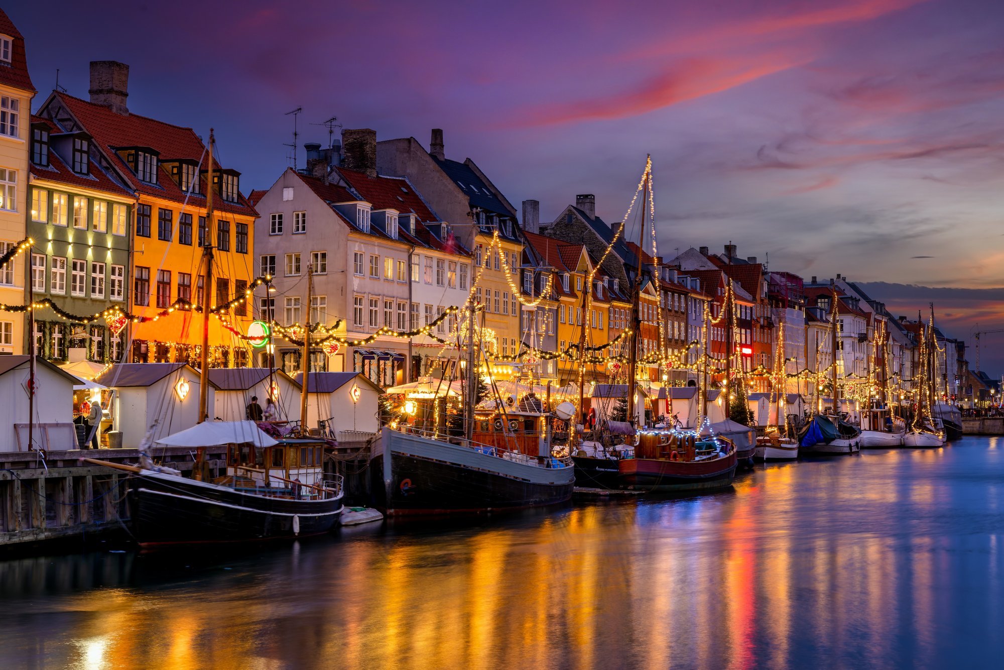 Nyhavn in Kopenhagen mit Lichterketten vor den bunten Häuserfassaden
