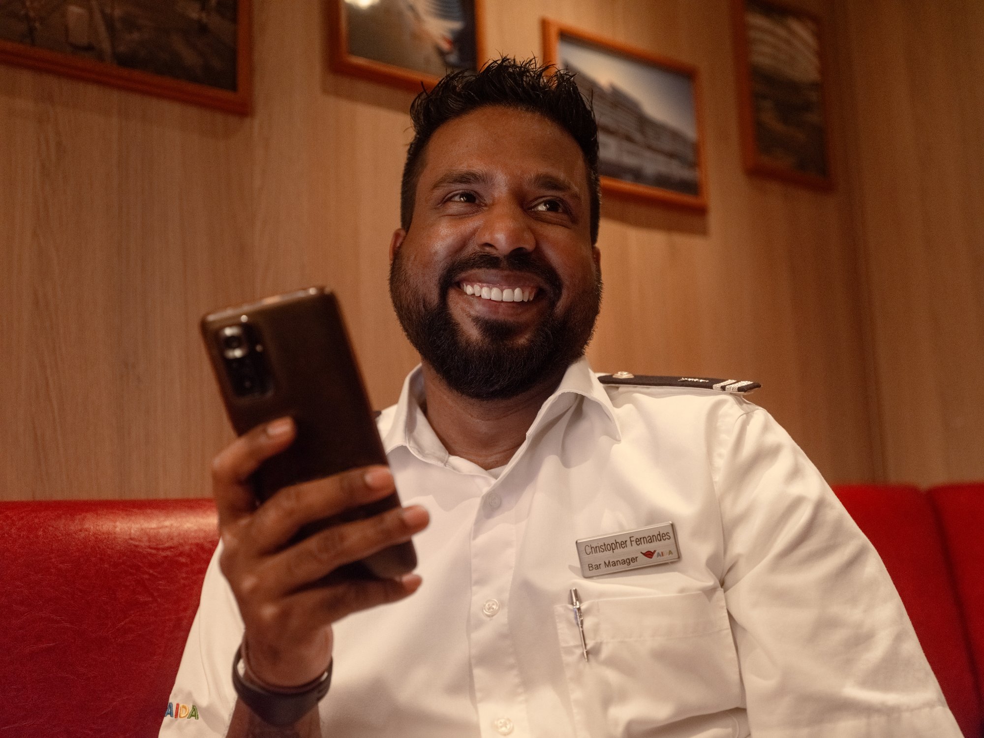 AIDA crew member in the crew area with mobile phone in hand
