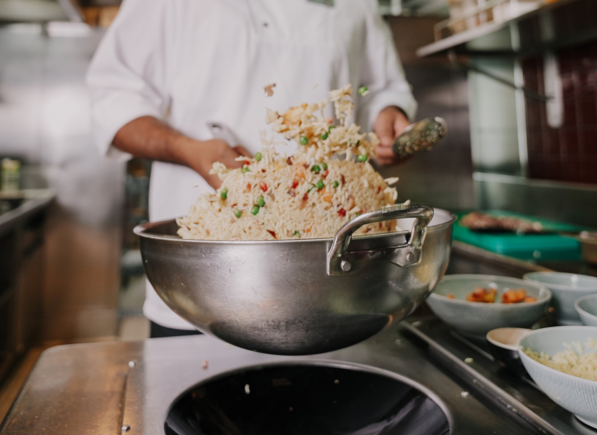 Koch schwenkt Wok mit Reis und Gemüse