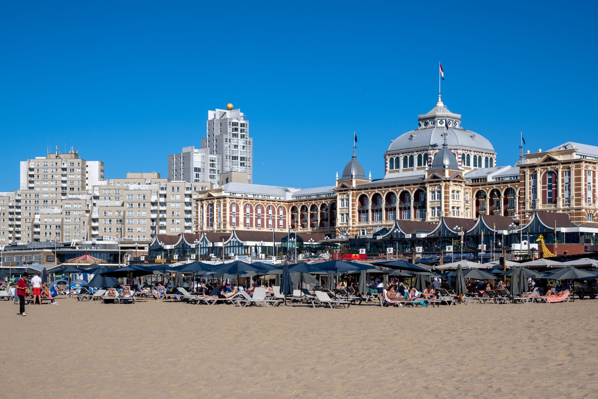 Het Kurhaus aan het strand van scheveningen, omringt door appartementen en strandtenten