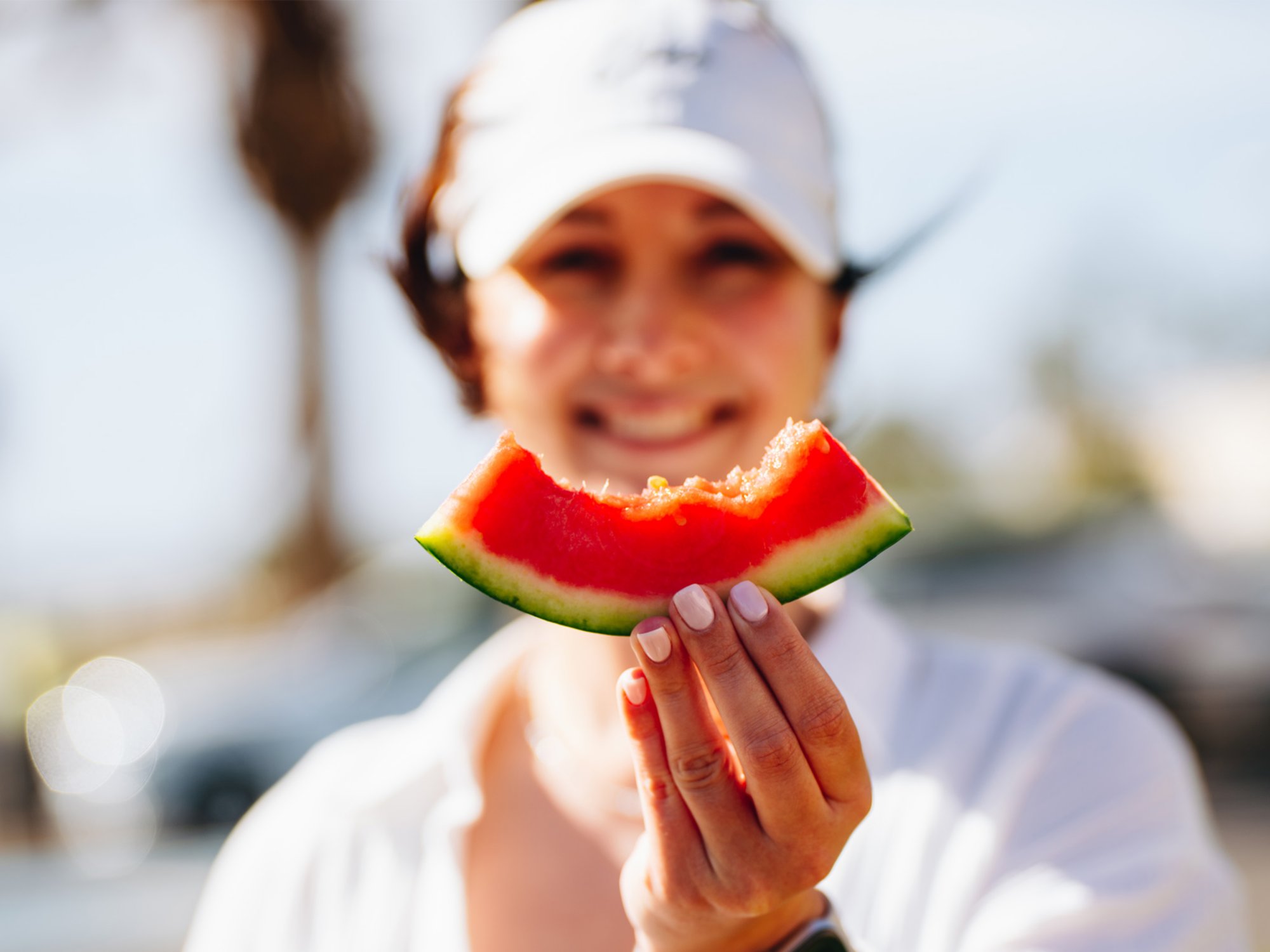 Frau hält ein angebissenes Stück Wassermelone hoch