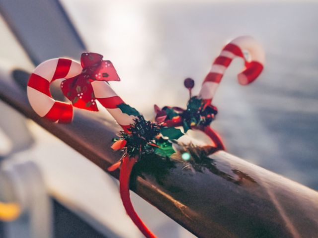 Weihnachtlich geschmückte Reling mit Blick auf das Meer.