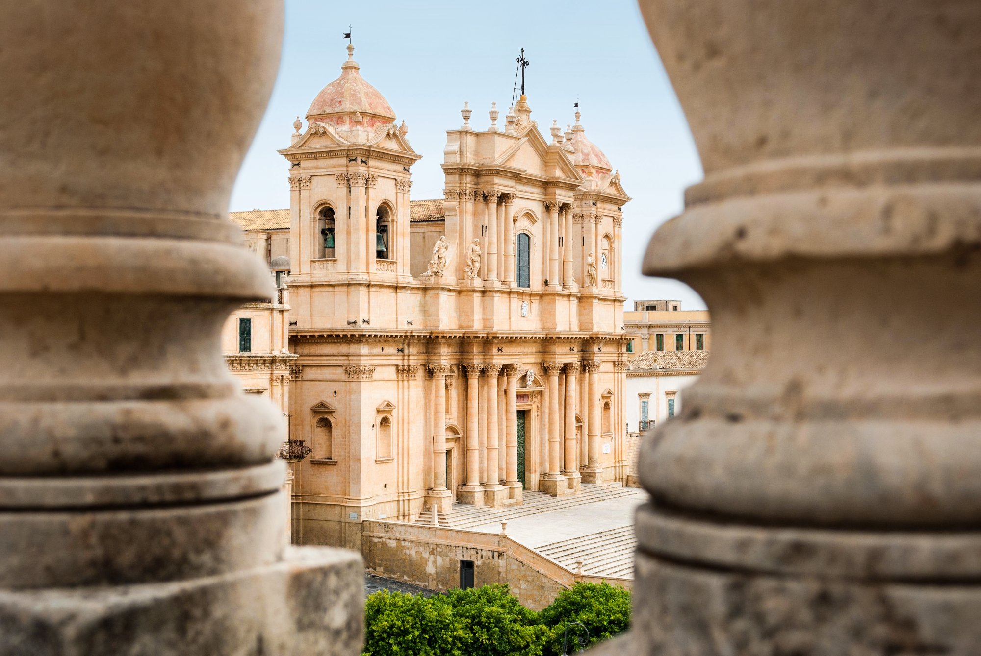 Historisches Gebäude in Catania mit klassizistischer Fassade, zwei Türmen mit Kuppeln und steinernen Balustern im Vordergrund.