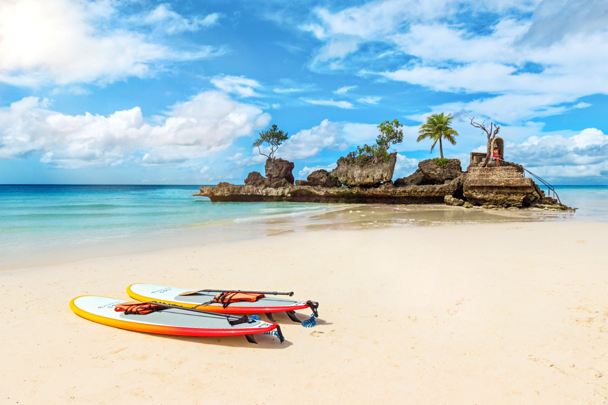 Surfboards on the White Beach, in the background the iconic rock with Mother Mary (Willy s Rock). White Beach on Boracay island has been voted one of the most beautiful beaches in the world.