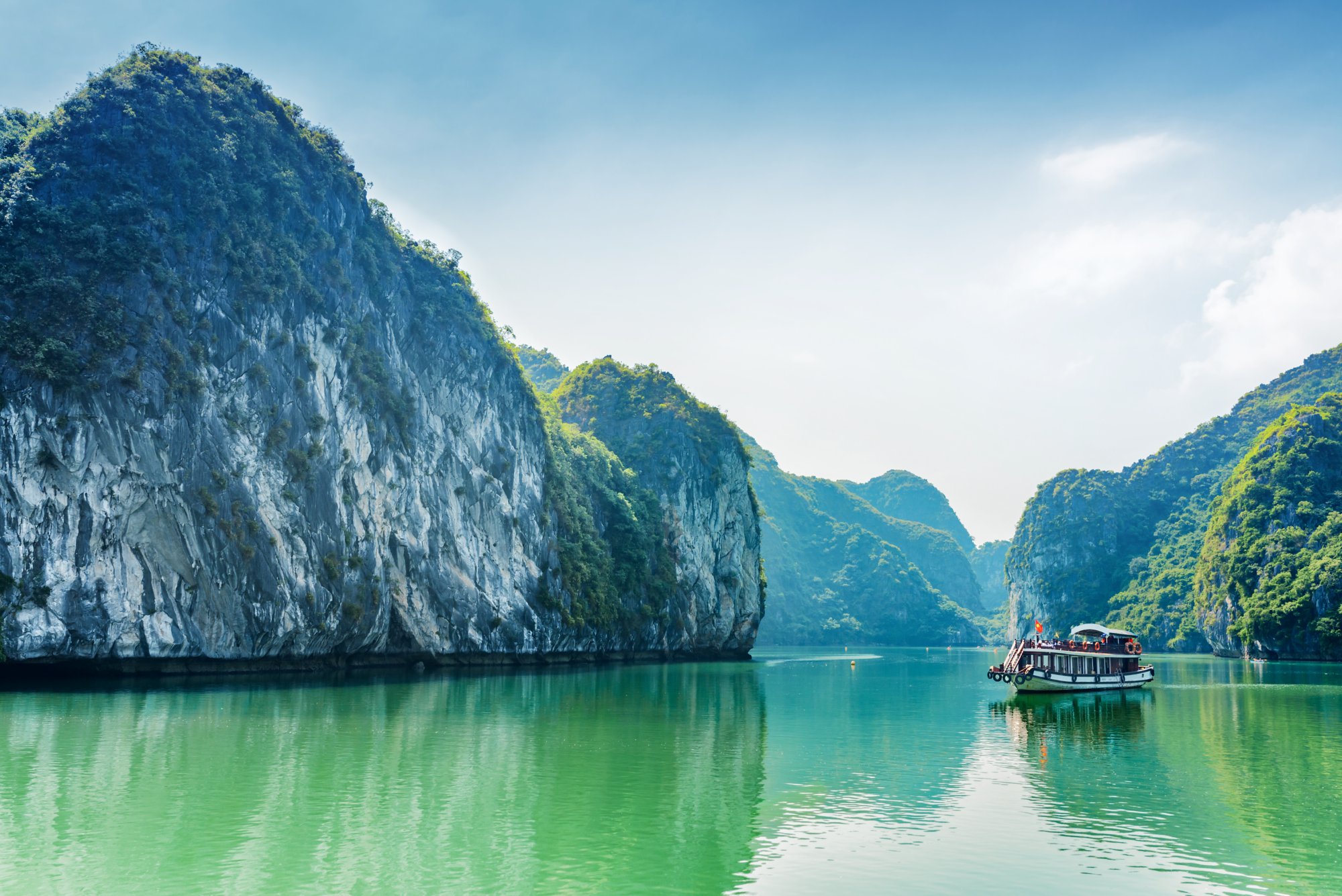 Tourist boat in the Halong Bay (Descending Dragon Bay) at the Gulf of Tonkin of the South China Sea, Vietnam. Landscape formed by karst isles. The Ha Long Bay is a popular tourist destination of Asia