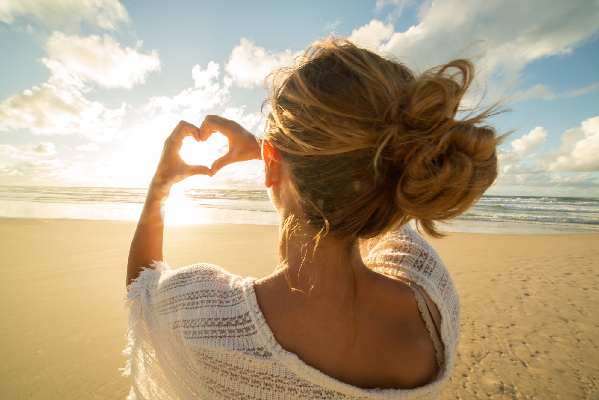 Eine Frau zeigt mir ihren Händen ein Herz Richtung Himmel