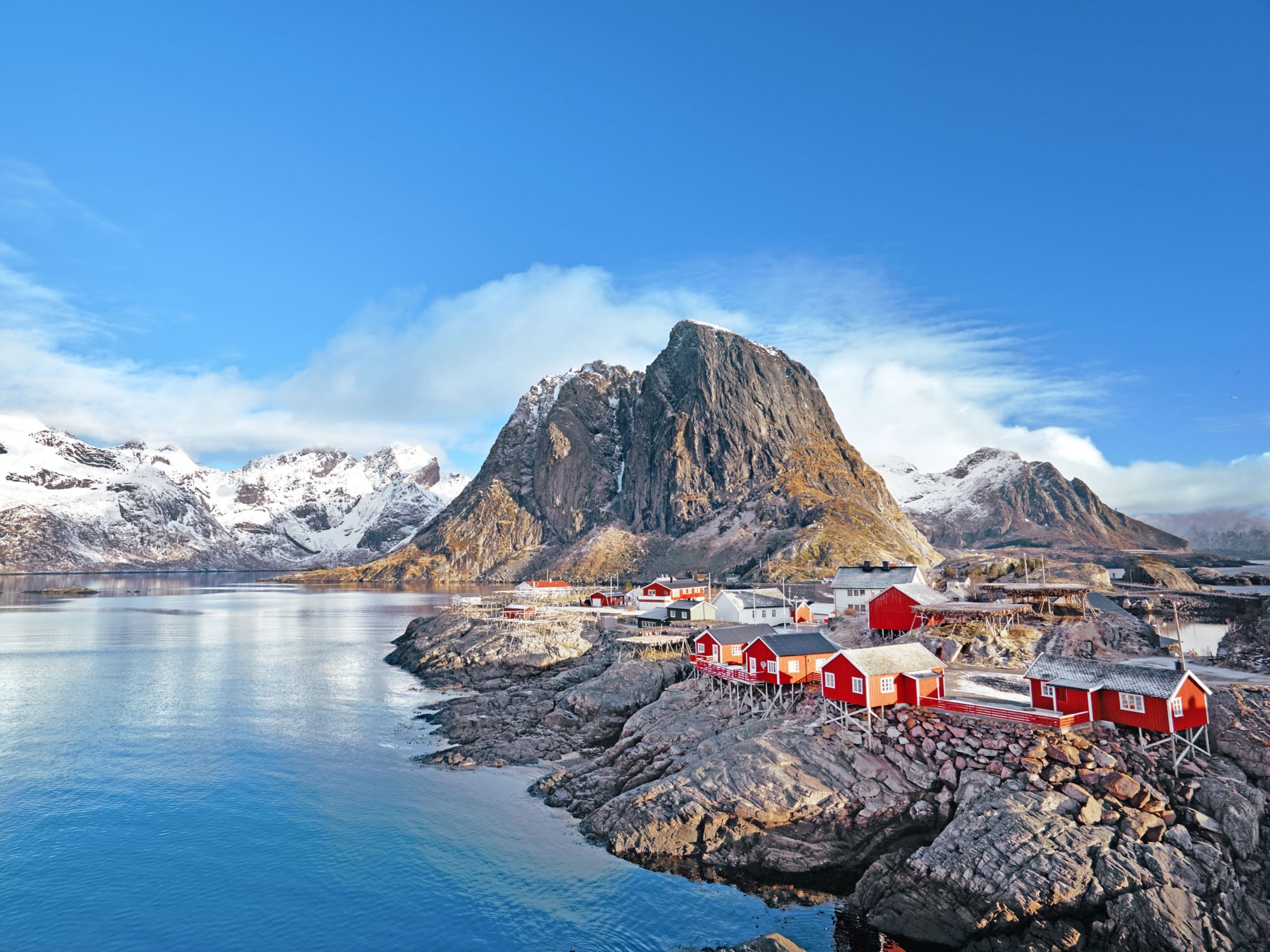 Verschneite norwegische Küste mit roten Häusern und Fjord.