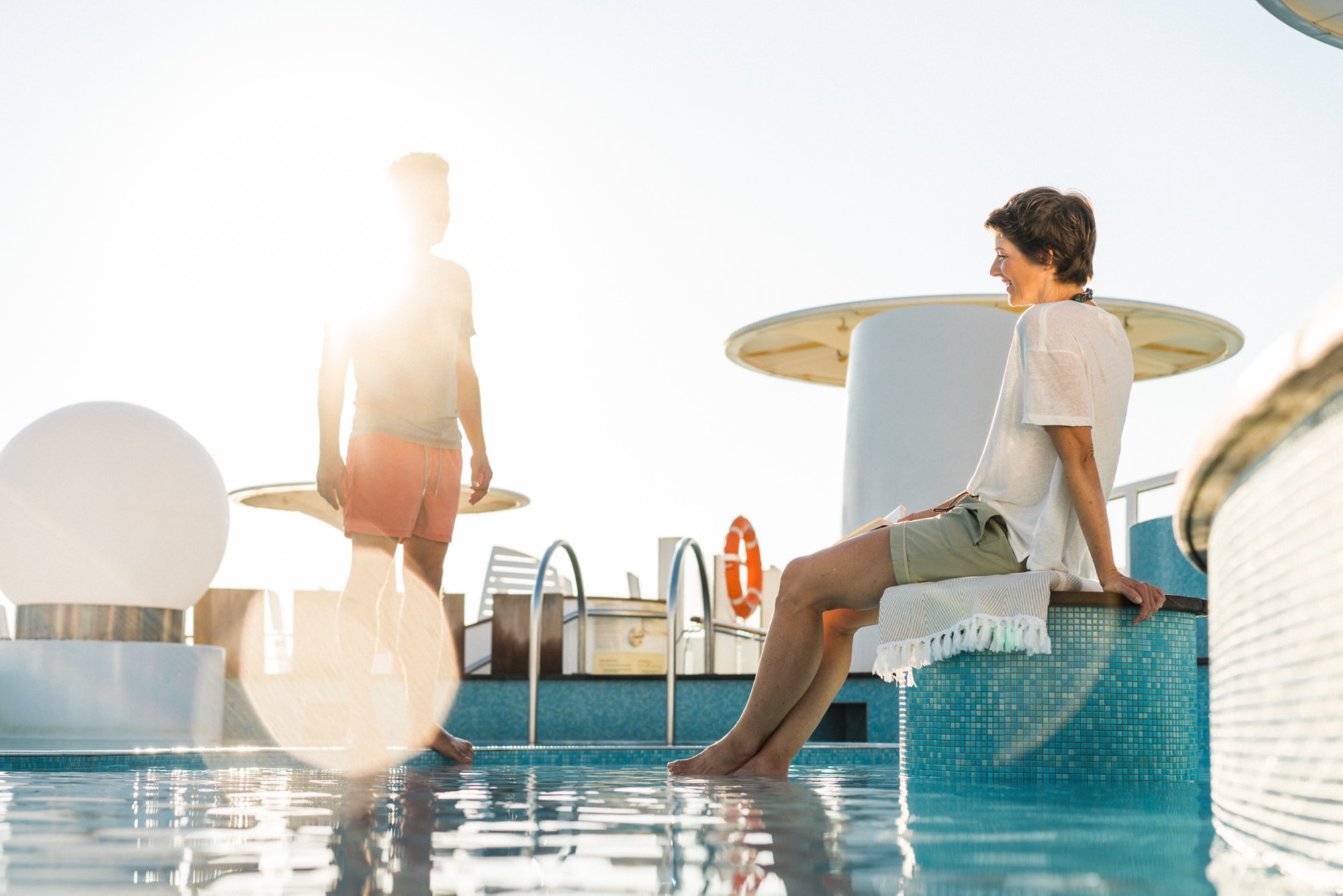 Frau sitzt am Swimmingpool