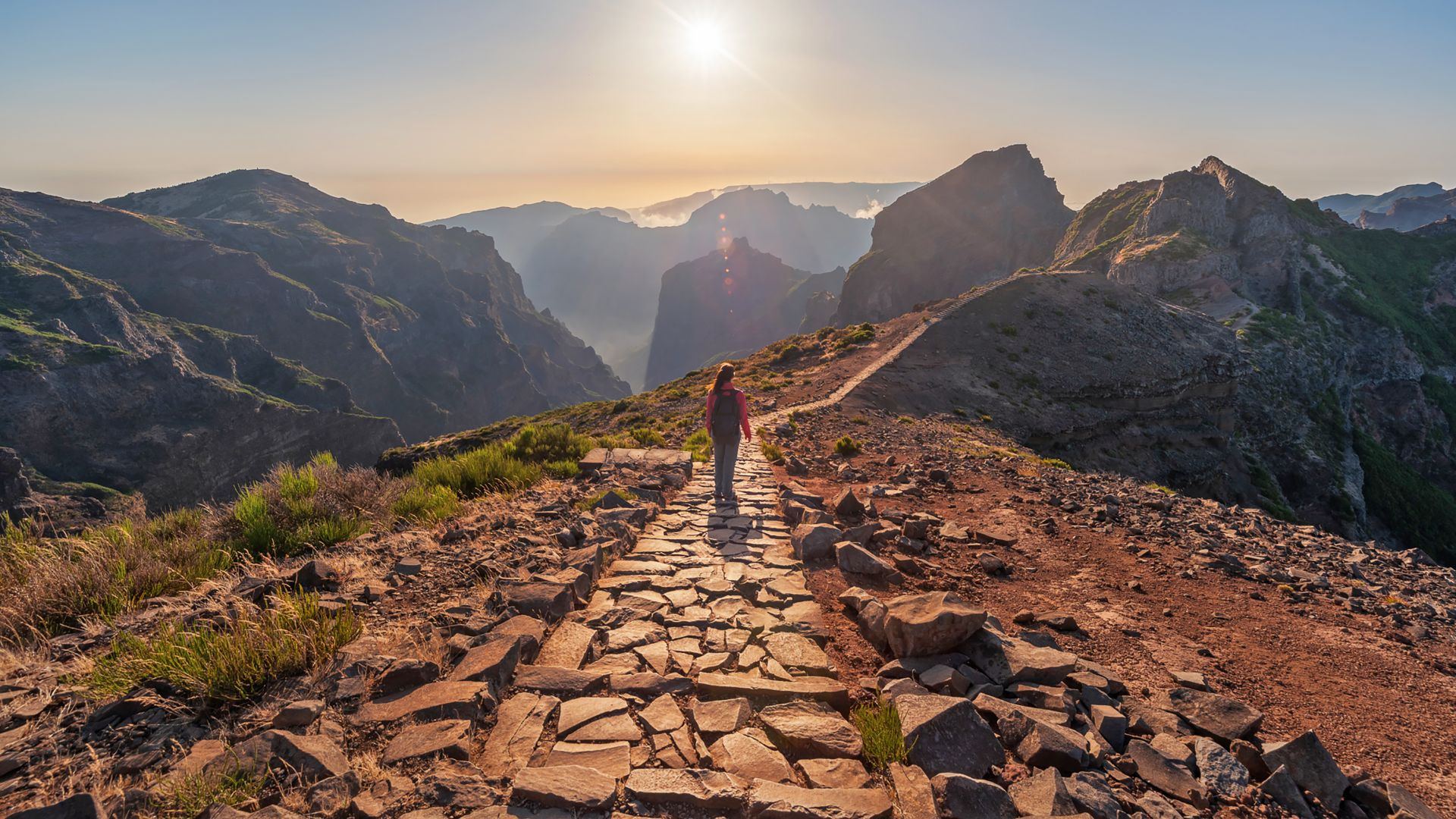 Woman standing and watching the mountains in path that joins Arieiro peak and Ruivo peak in Madeira Island