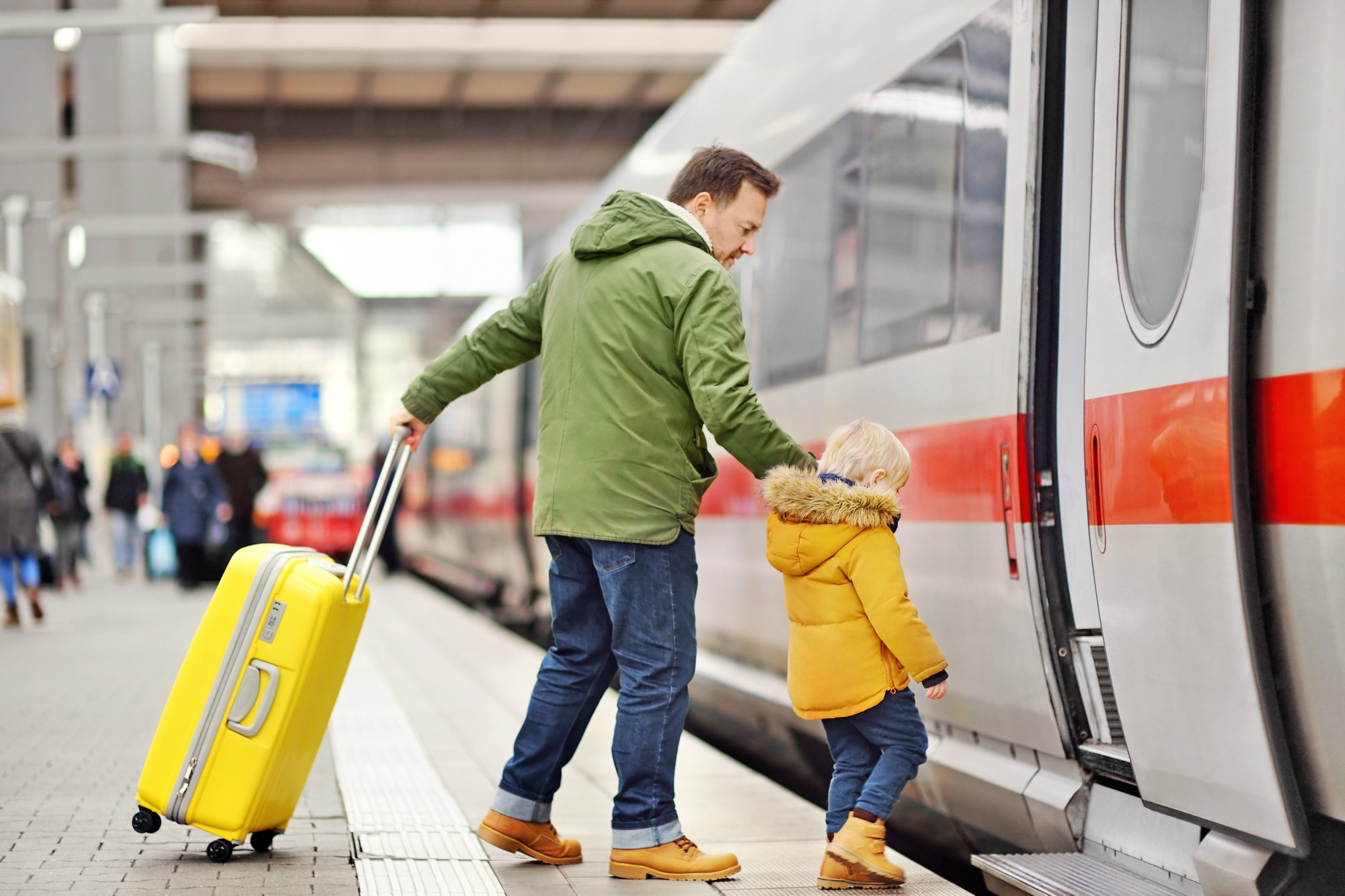 Little boy and his father go in express train on railway station platform. Travel, tourism, winter vacation and family concept. Man and his son together.