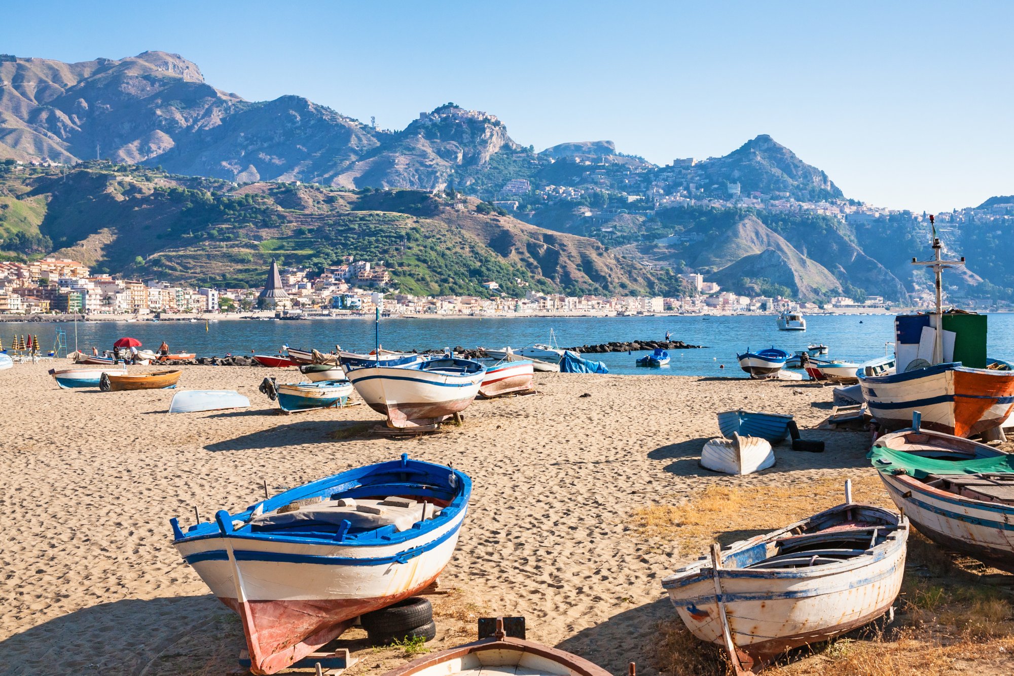 travel to Italy - boats on urban beach in giardini naxos town in Sicily in summer morning