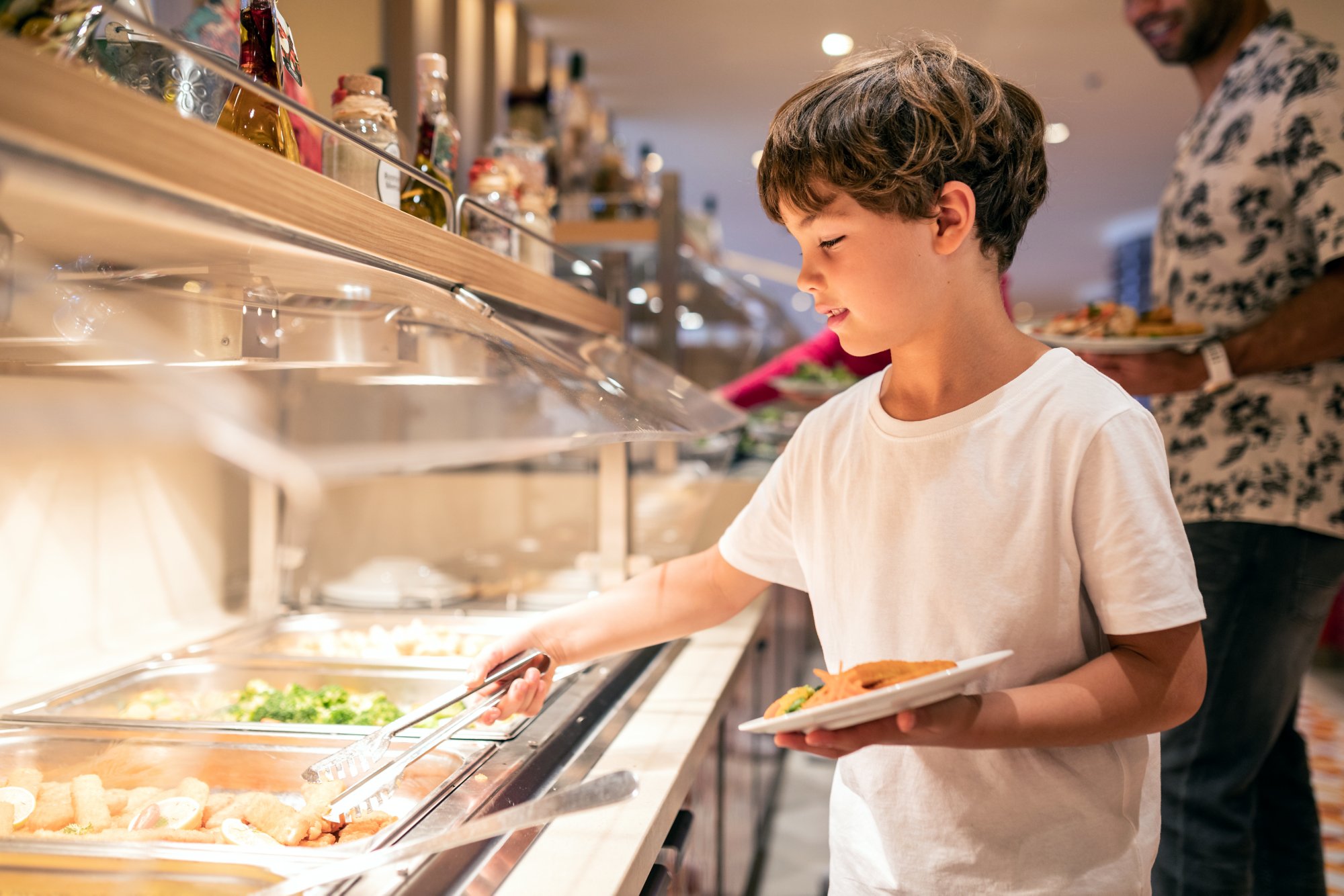 Junge im Buffet-Restaurant beim Teller auffüllen