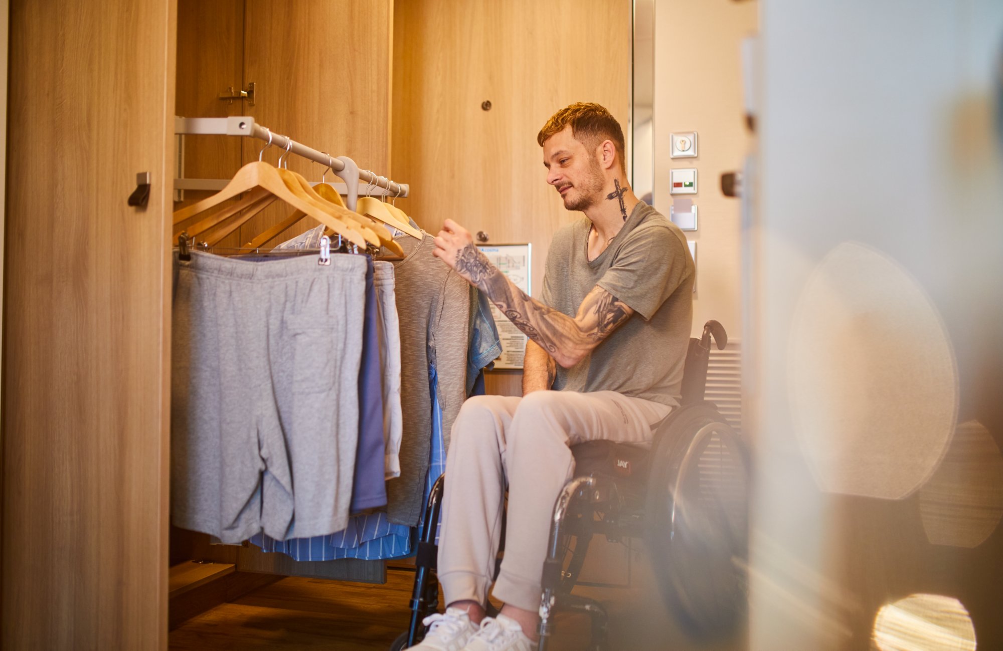 Mann im Rollstuhl benutzt  herunterklappbaren Kleiderschrank