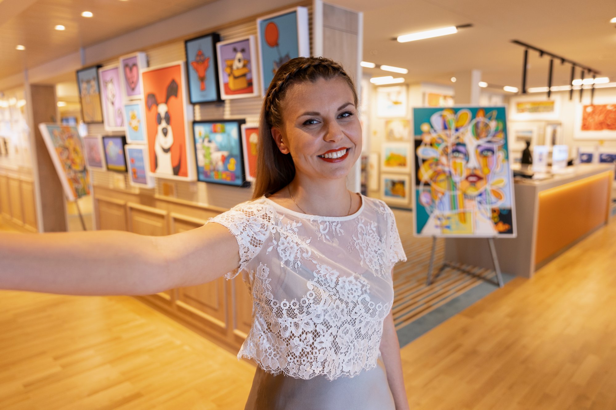 AIDA Galeristin macht ein Selfie mit Kunstwerken im Hintergrund