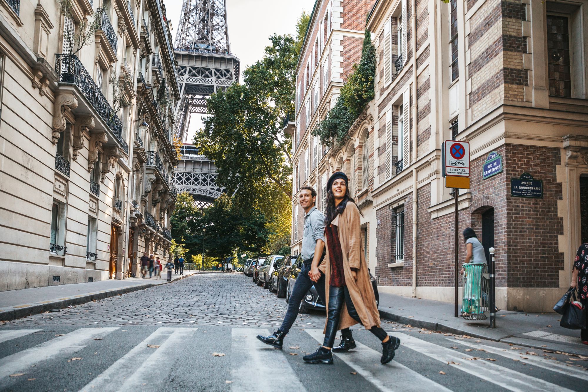 Straßenszene in Paris mit Kopfsteinpflaster, klassischer Architektur und Blick auf den Eiffelturm im Hintergrund.