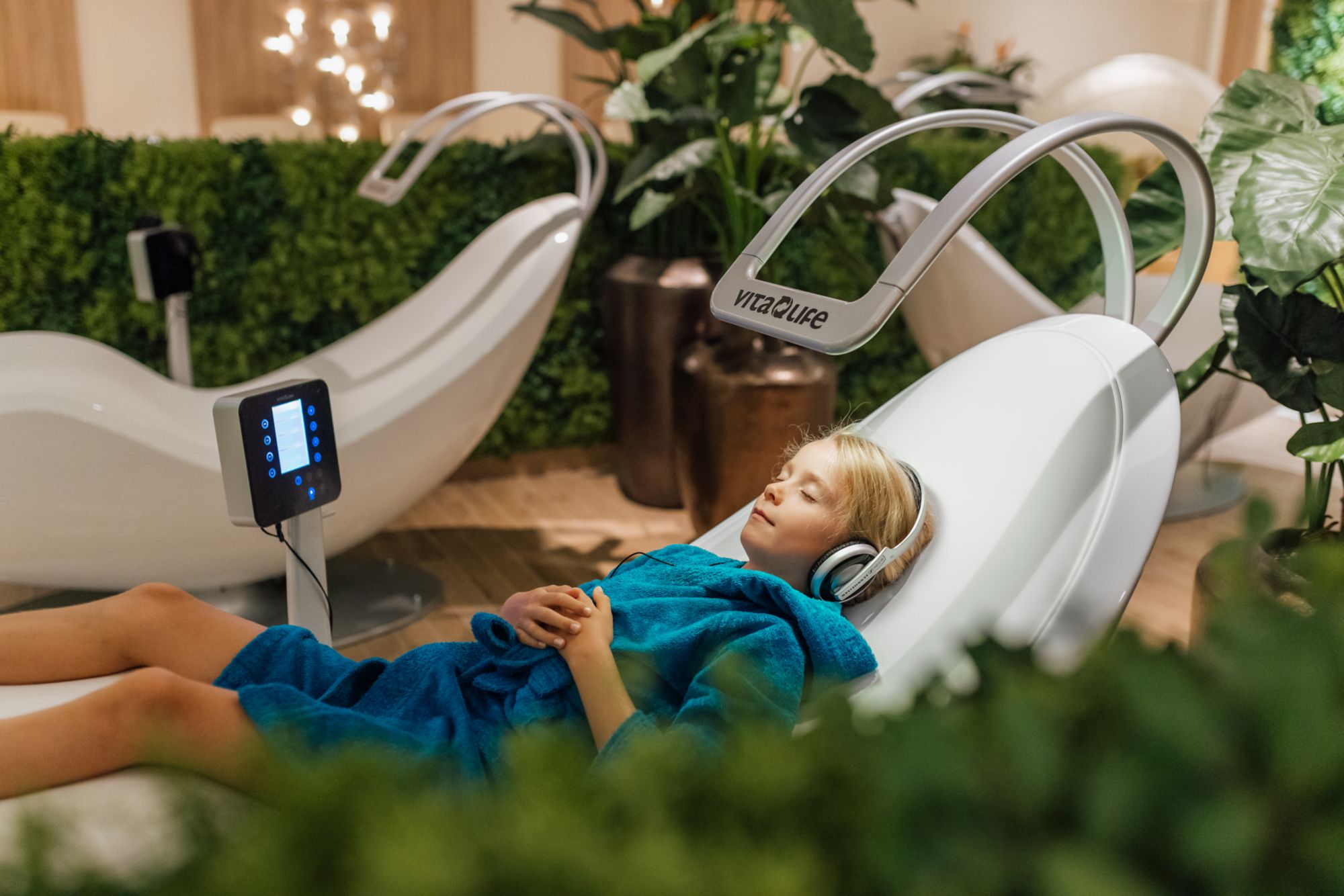 Ein Kind mit Kopfhörern liegt auf einer Spa-Liege.