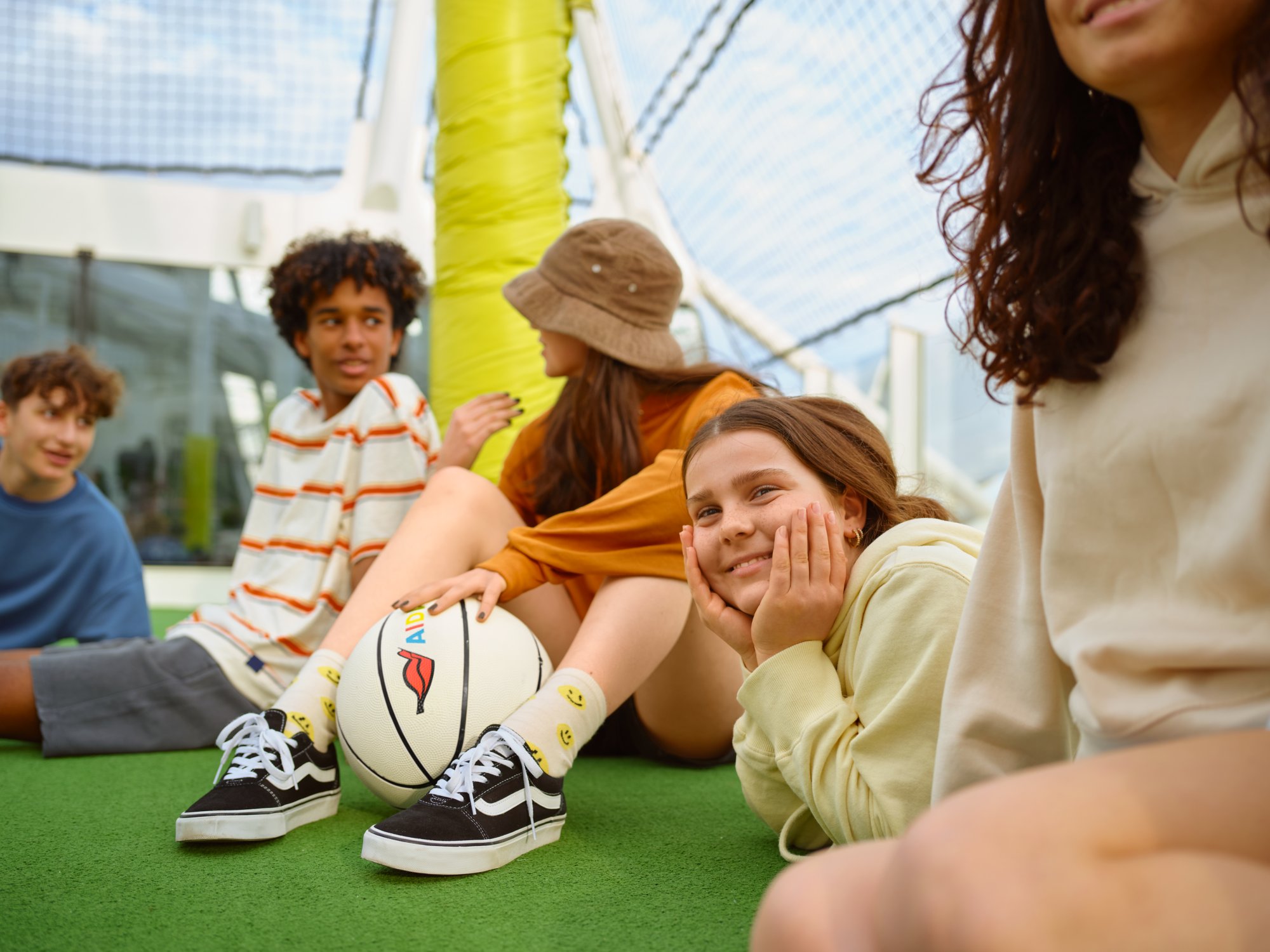 Kinder sitzen an Bord. Auf dem Boden liegt ein Basketball.