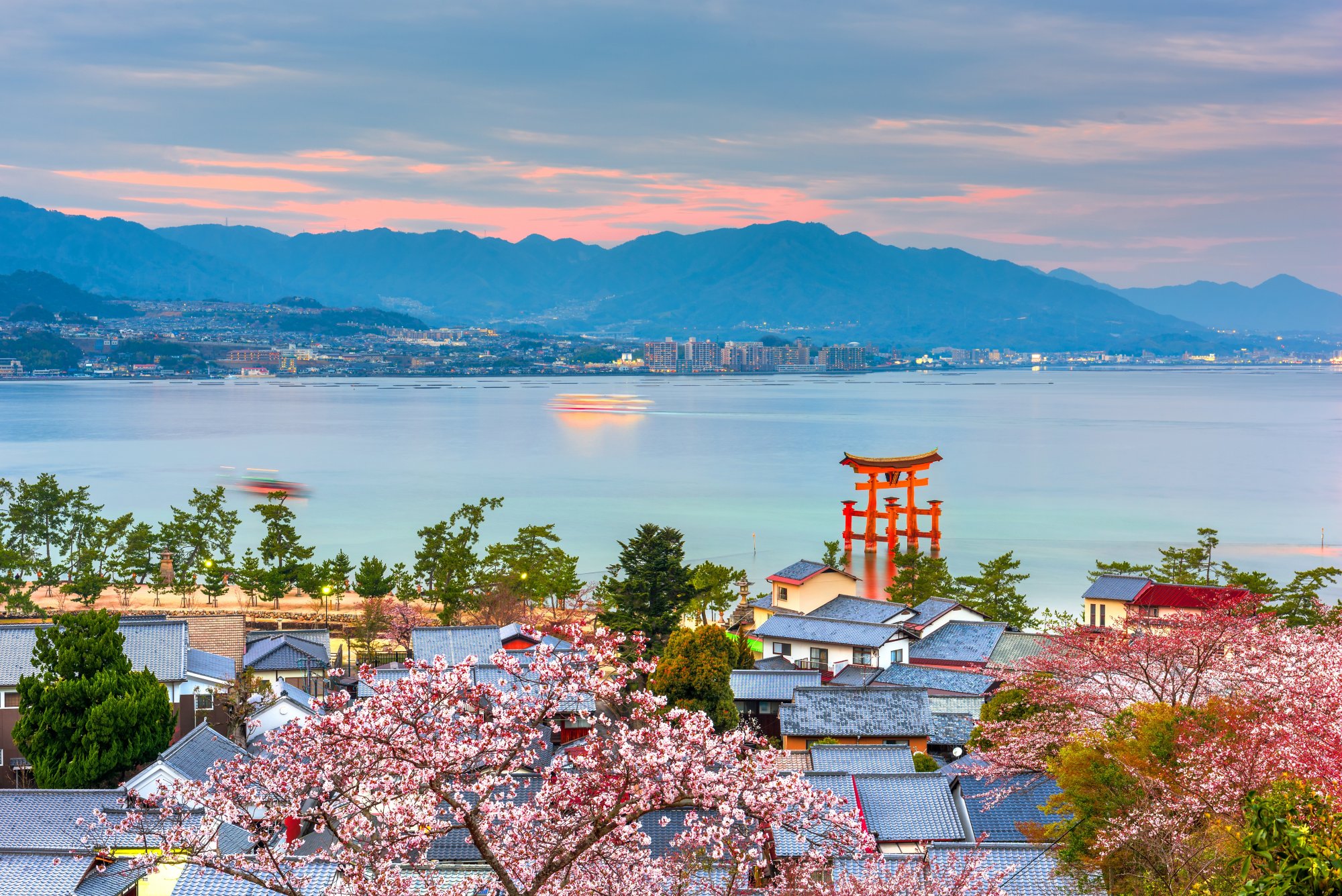 Miyajima Island, Hiroshima, Japan with temples on the Seto Inland Sea at dusk in the spring season.