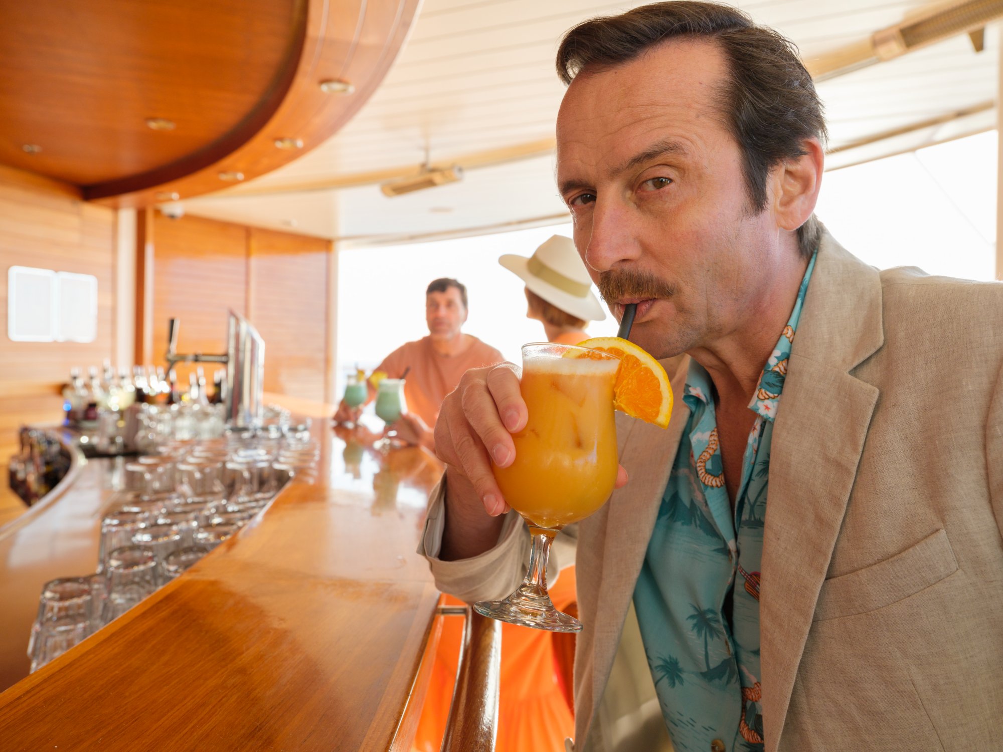 Mann trinkt Orangensaft an einer Bar.