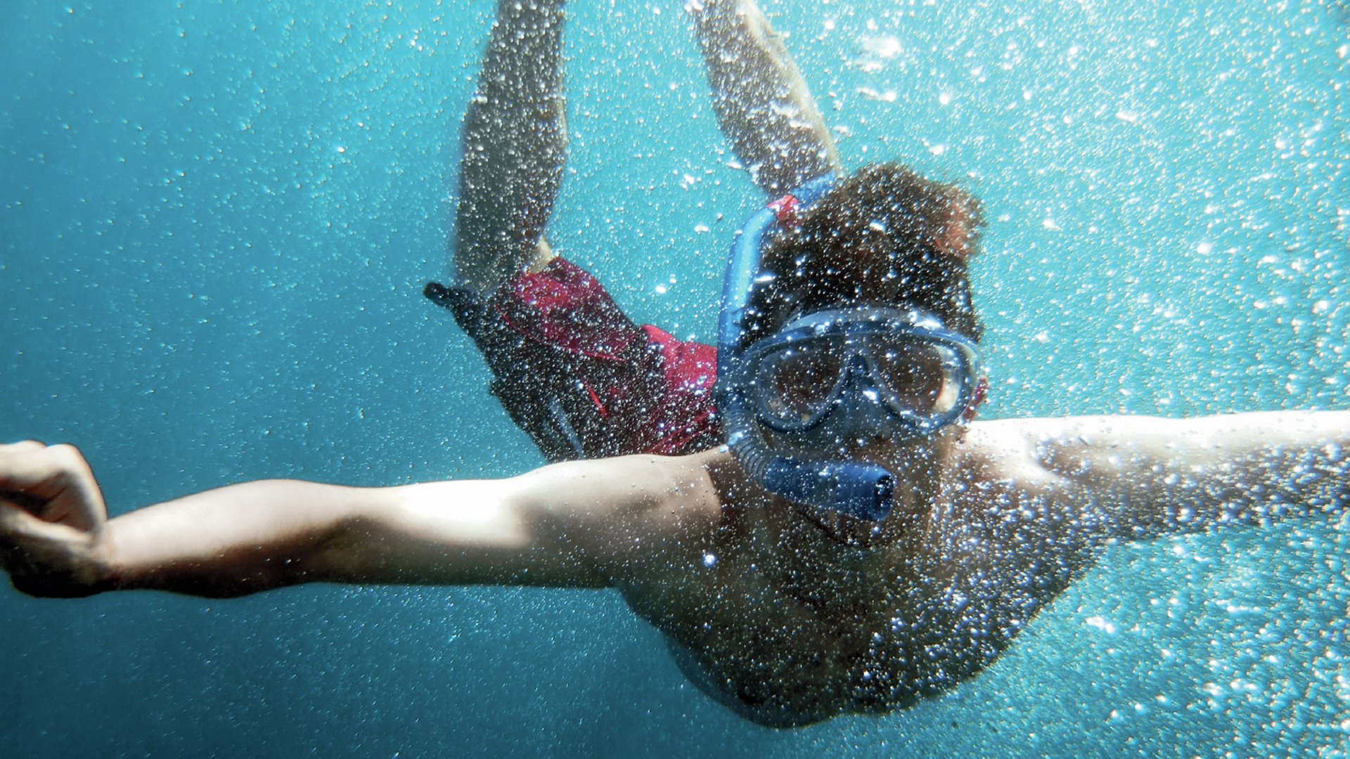 young men dive in blue sea with a lot of bubbles