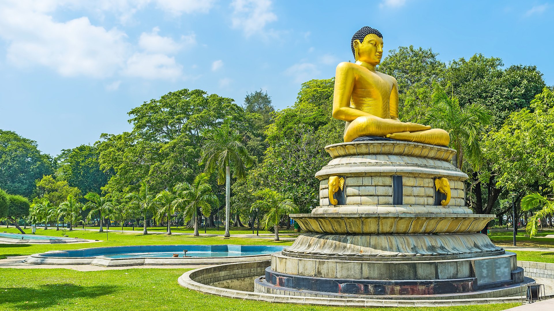 The giant golden statue of Meditating Lord Buddha decorates the central alley of Viharamahadevi (former Victoria) park, Colombo, Sri Lanka.