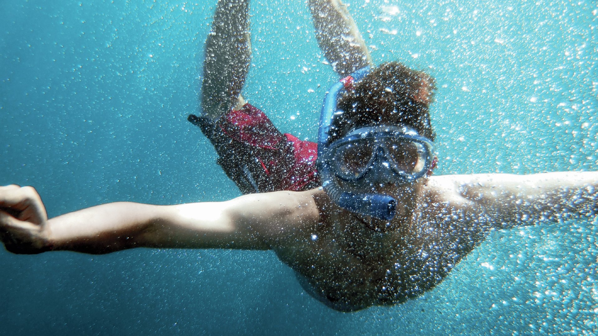 young men dive in blue sea with a lot of bubbles