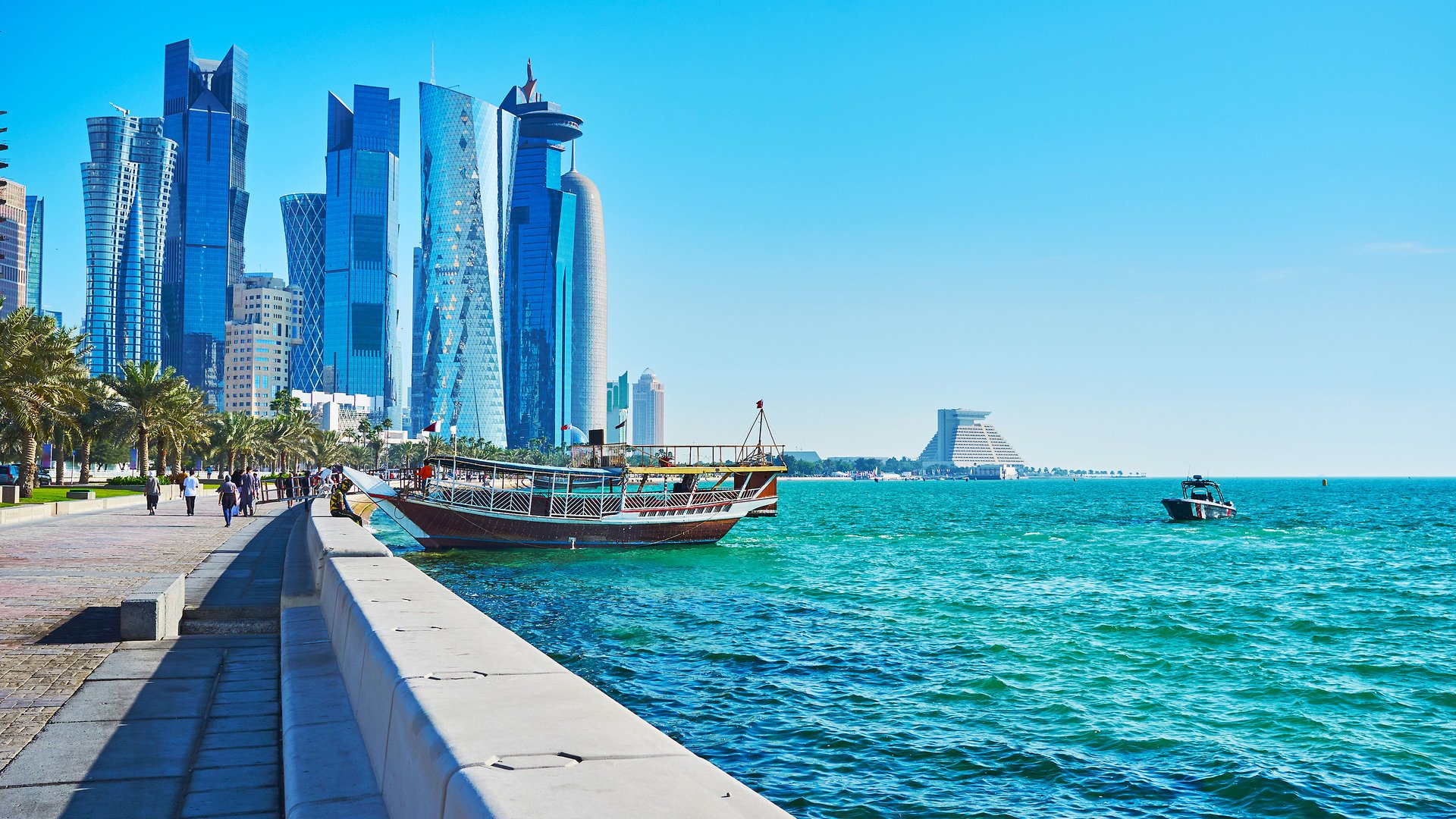The pleasure boats at the coast of West Bay, the glass skyscrapers of Al Dafna business district are seen on background, Doha, Qatar.