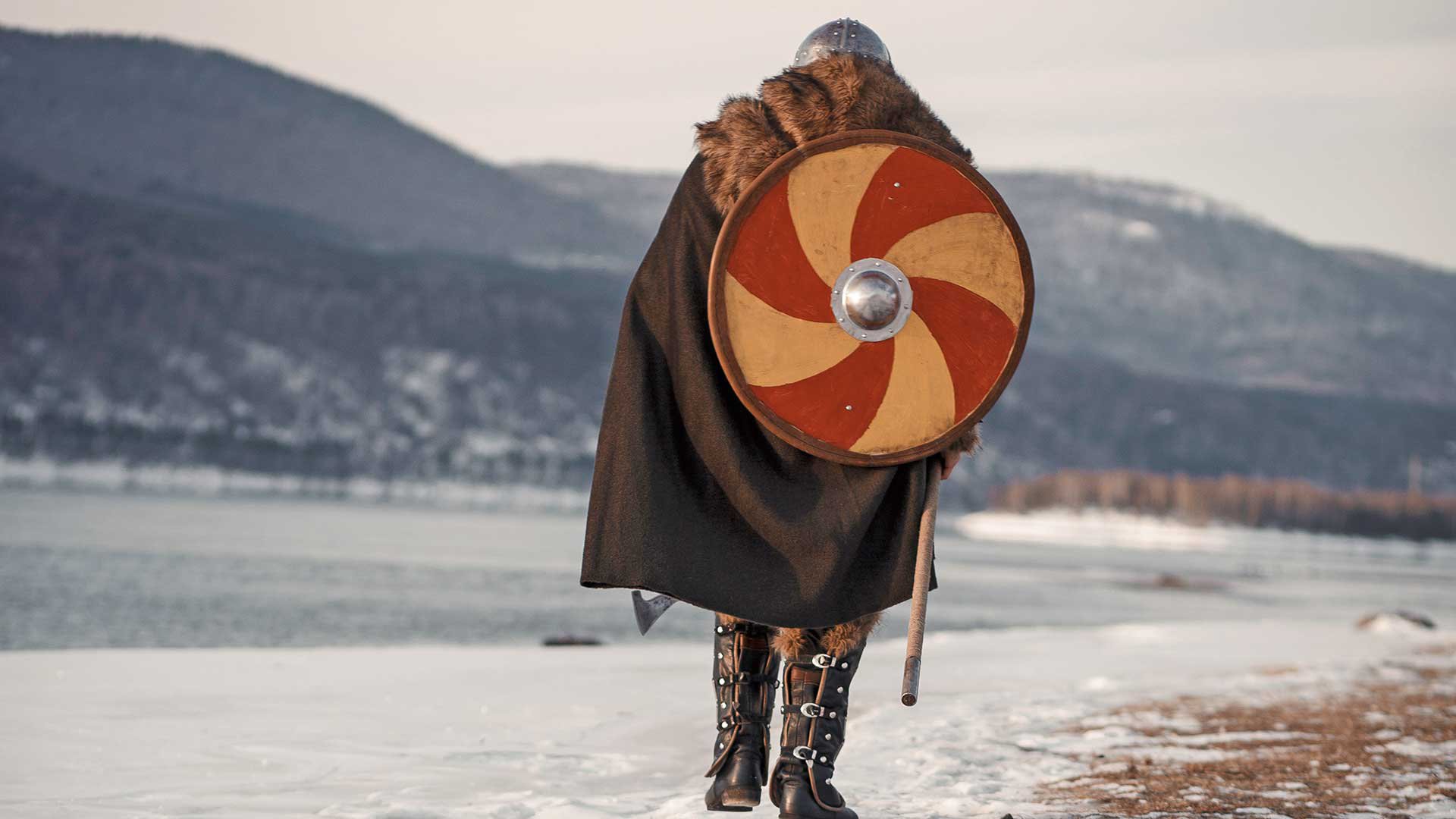 Medieval Scandinavian warrior Viking in full outfit on shore of winter sea