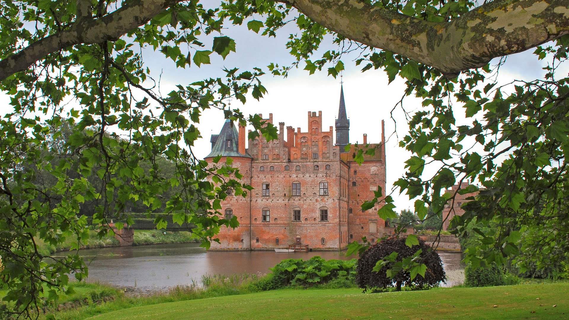 Fairytale like medieval Egeskov Castle on the island of Funen in Denmark seen through the lush of a tree