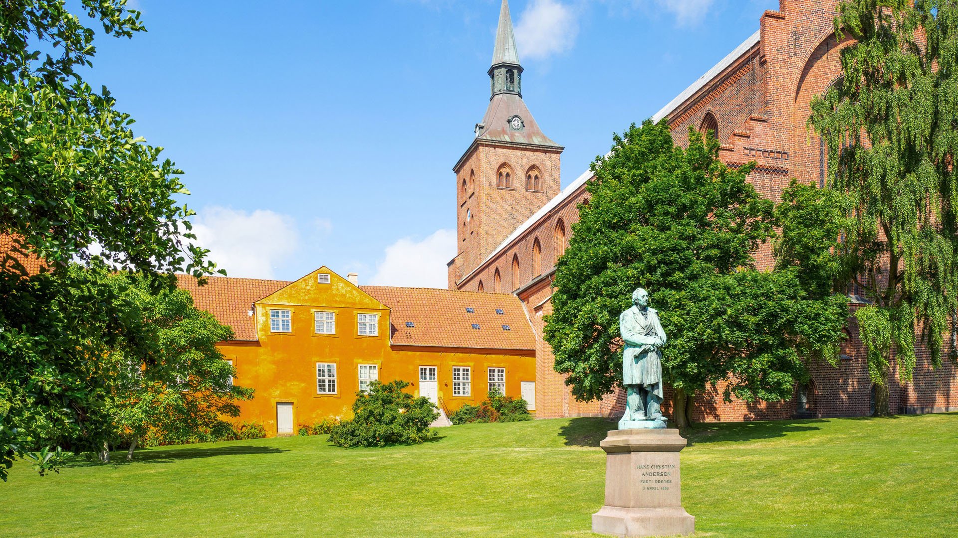 63189911 - odense, the gothic st. canute's cathedral with the hans christian andersen monument in the foreground