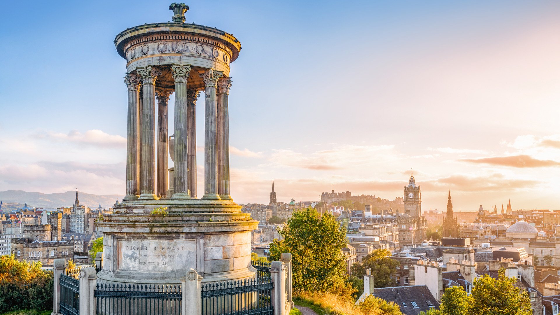 A view over central Edinburgh at sunset, taken from Calton Hill, with the stone memorial to  Dugald Stewart (1753 - 1828) in the foreground.