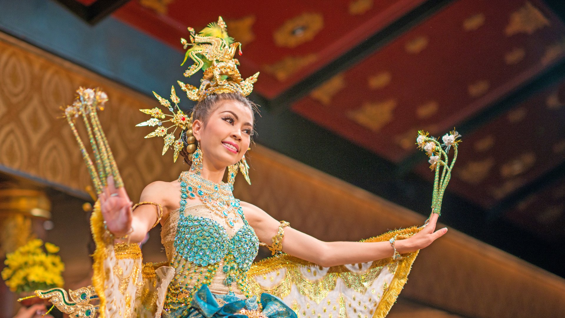 A beautiful thai dancer performs the Kinnaree Procession. Dressed as a half-bird-half-female creature the heroine brings good luck to her residents. Nikon D800e. 85mm 1.4 to catch the ambient light and mood. Copy space on the right.