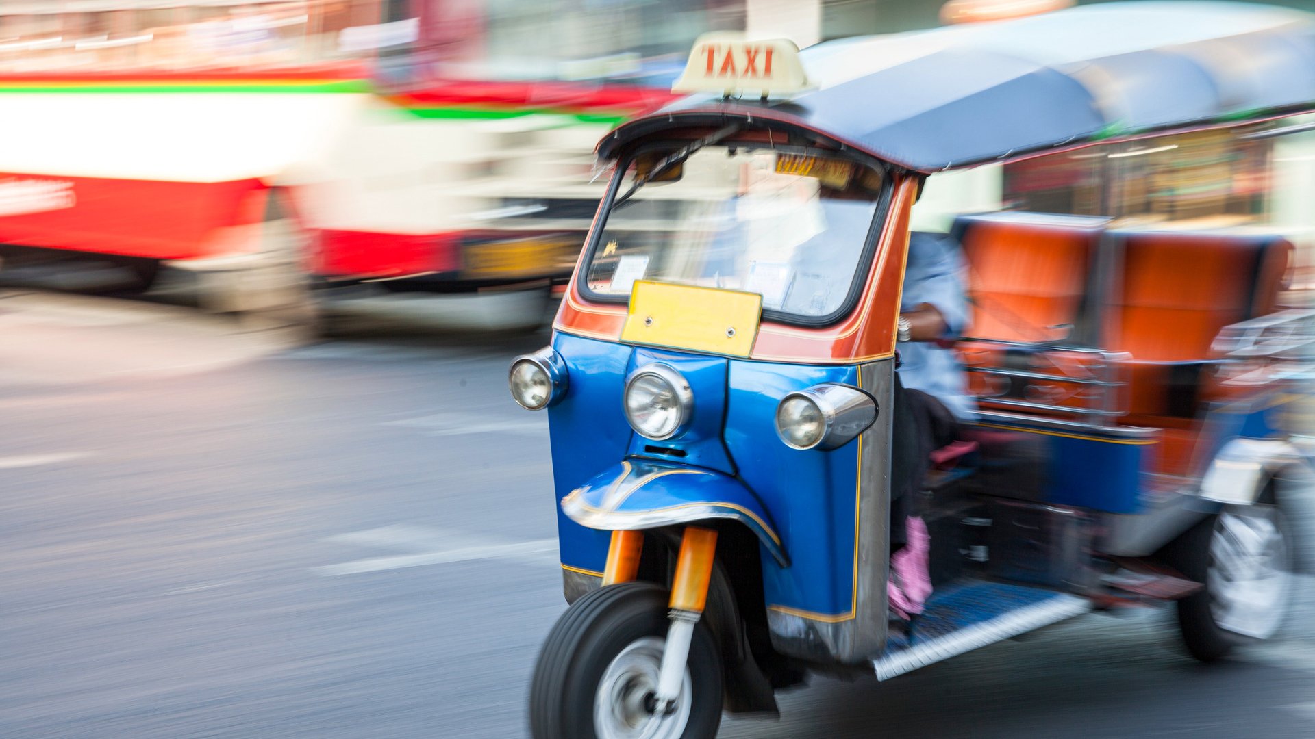 Man riding tuk-tuk on the street of Bangkok, Thailand.