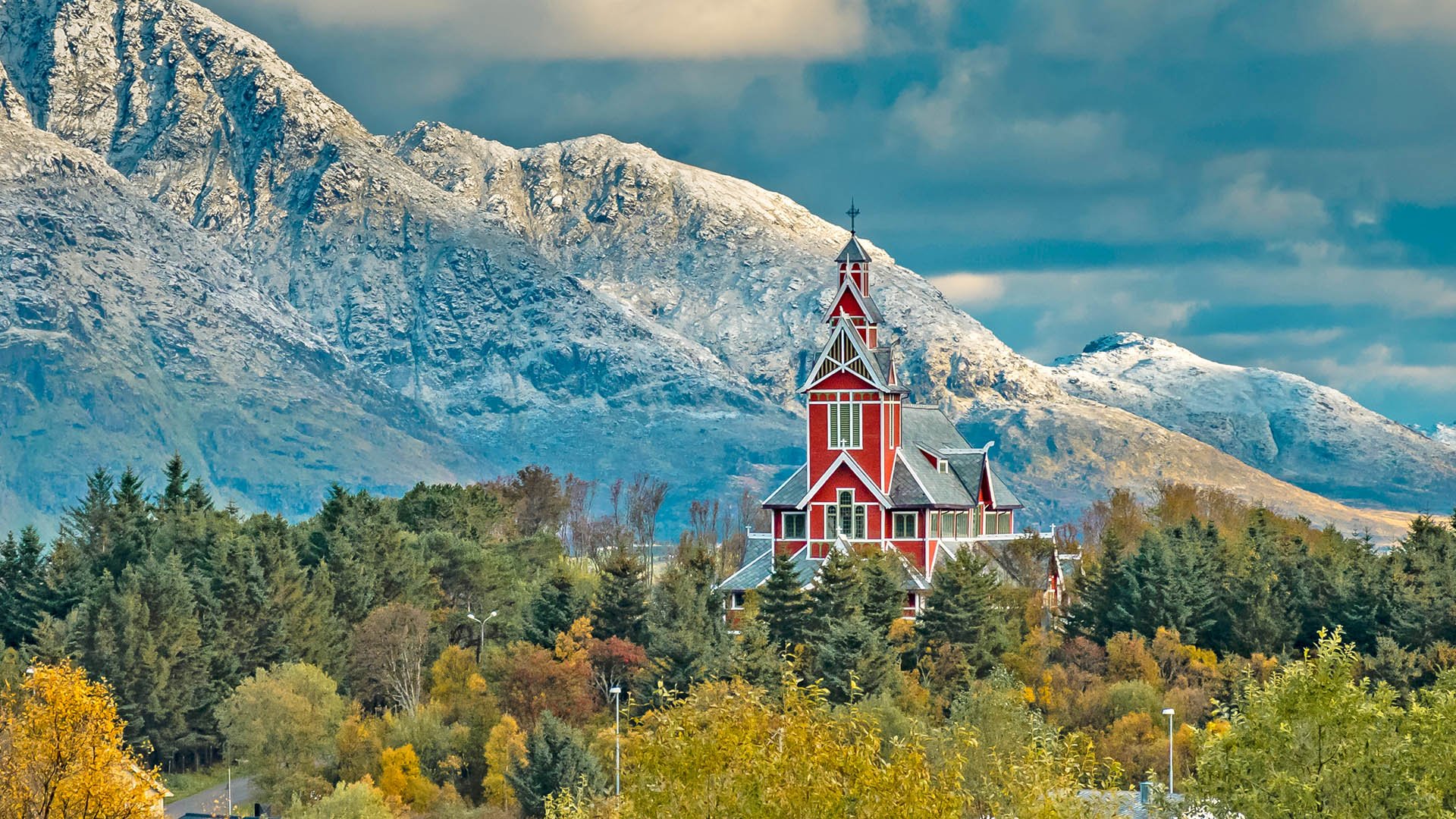 Red Buksnes church in the village of Gravdal  in front of the snowcovered summits of Himmeltindan at Lofoten Islands, Norway, in autumn