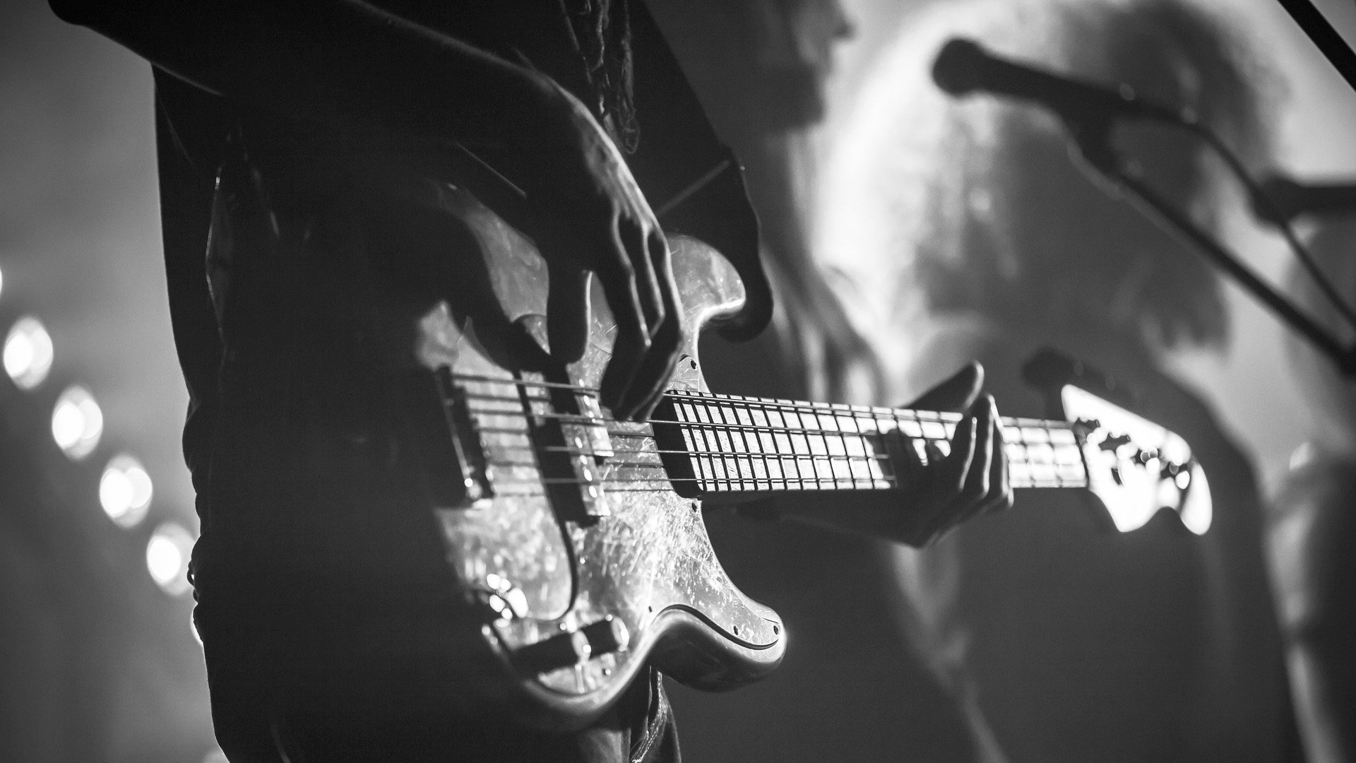 Close-up photo of electric bass guitar player, soft selective focus, live music theme, black and white