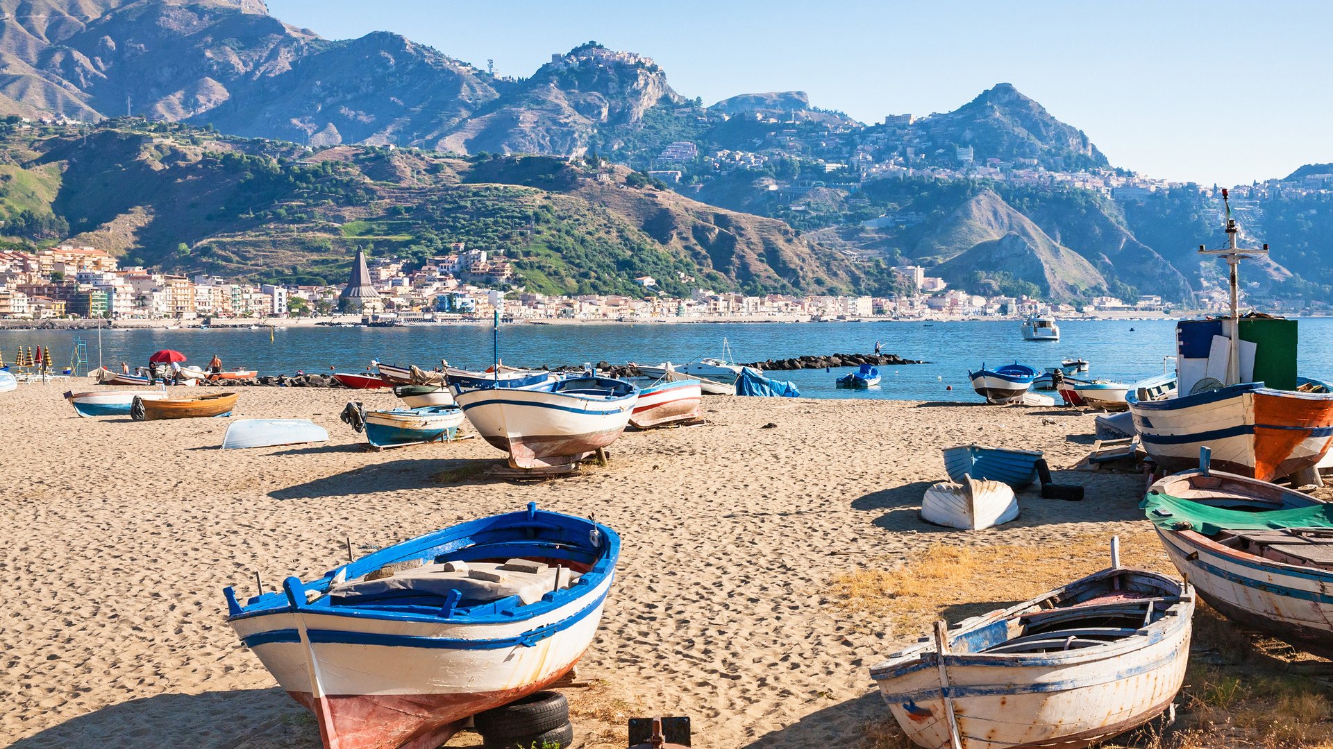 travel to Italy - boats on urban beach in giardini naxos town in Sicily in summer morning