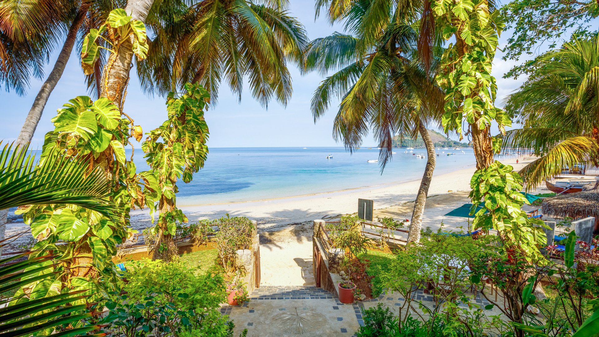 Path way to Nosy Be paradise beach with parasols and sunloungers, in background turquoise sea. North Madagascar. Africa vacation travel concept