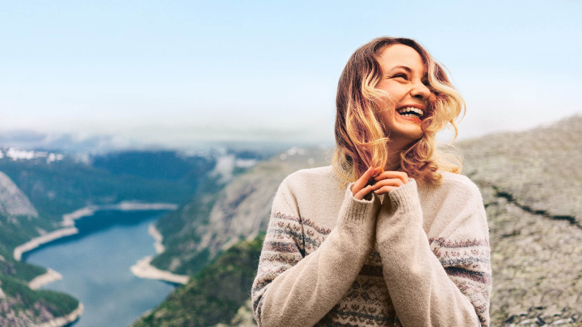 Girl standing on the Trolltunga and laughing 