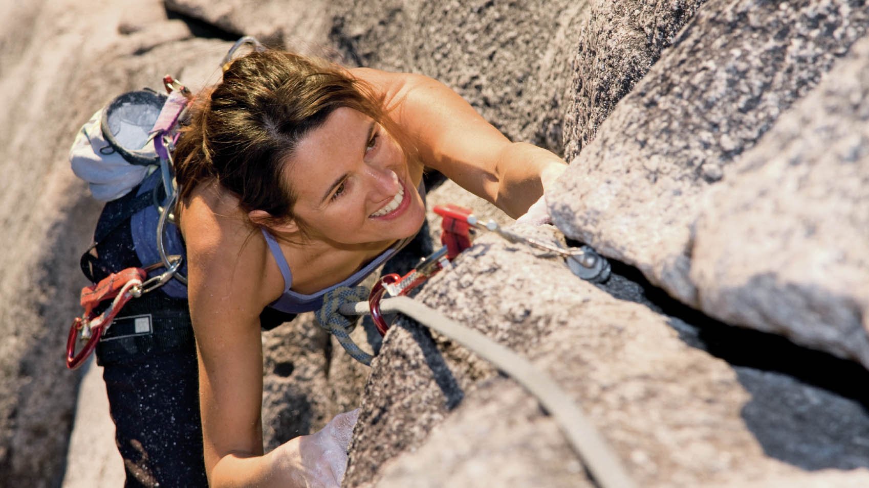 A fit and attractive girl climbs a granite rock in Squamish British Columbia Canada.