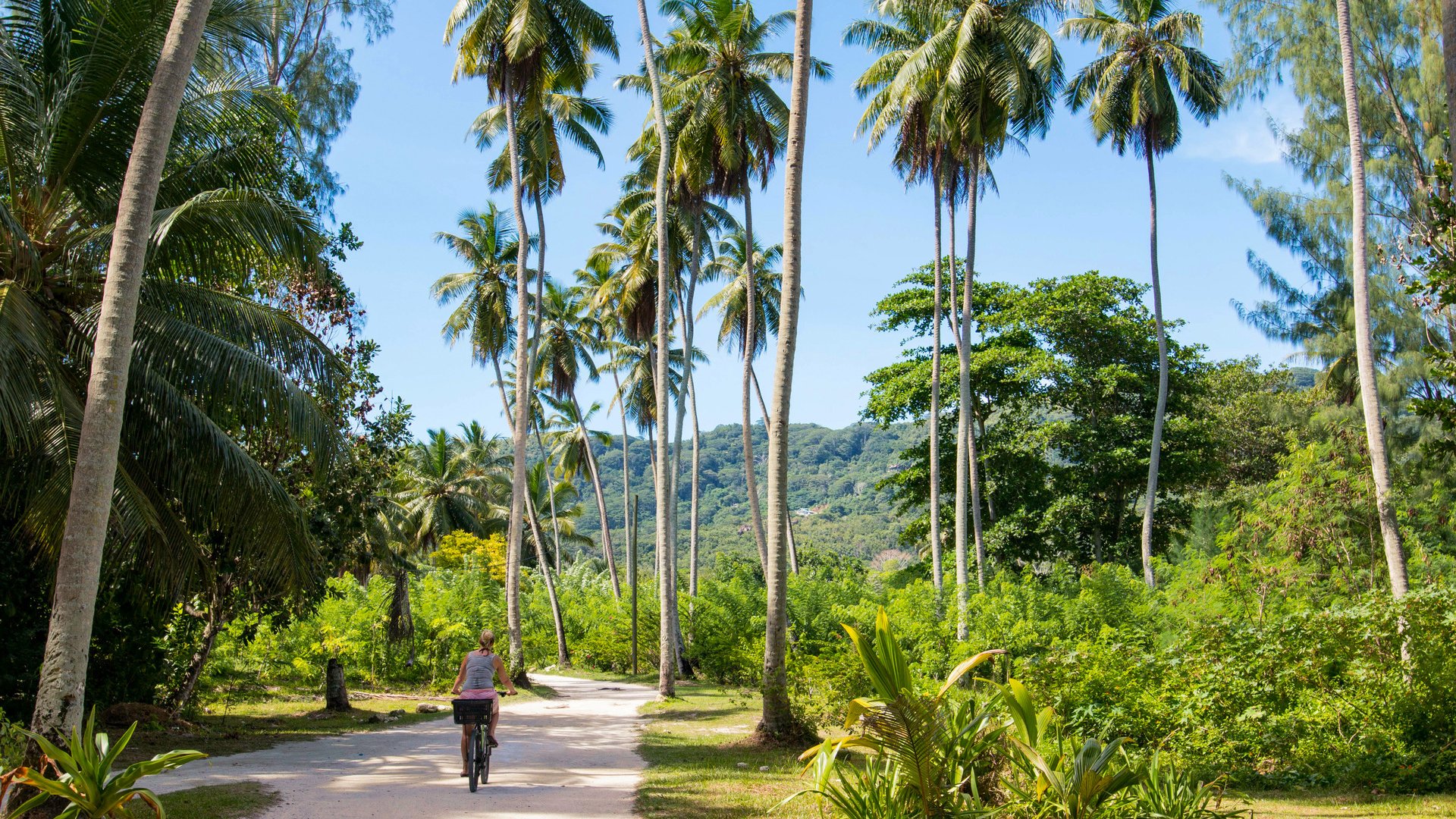 Woman bicycling on La Digue, Seychelles