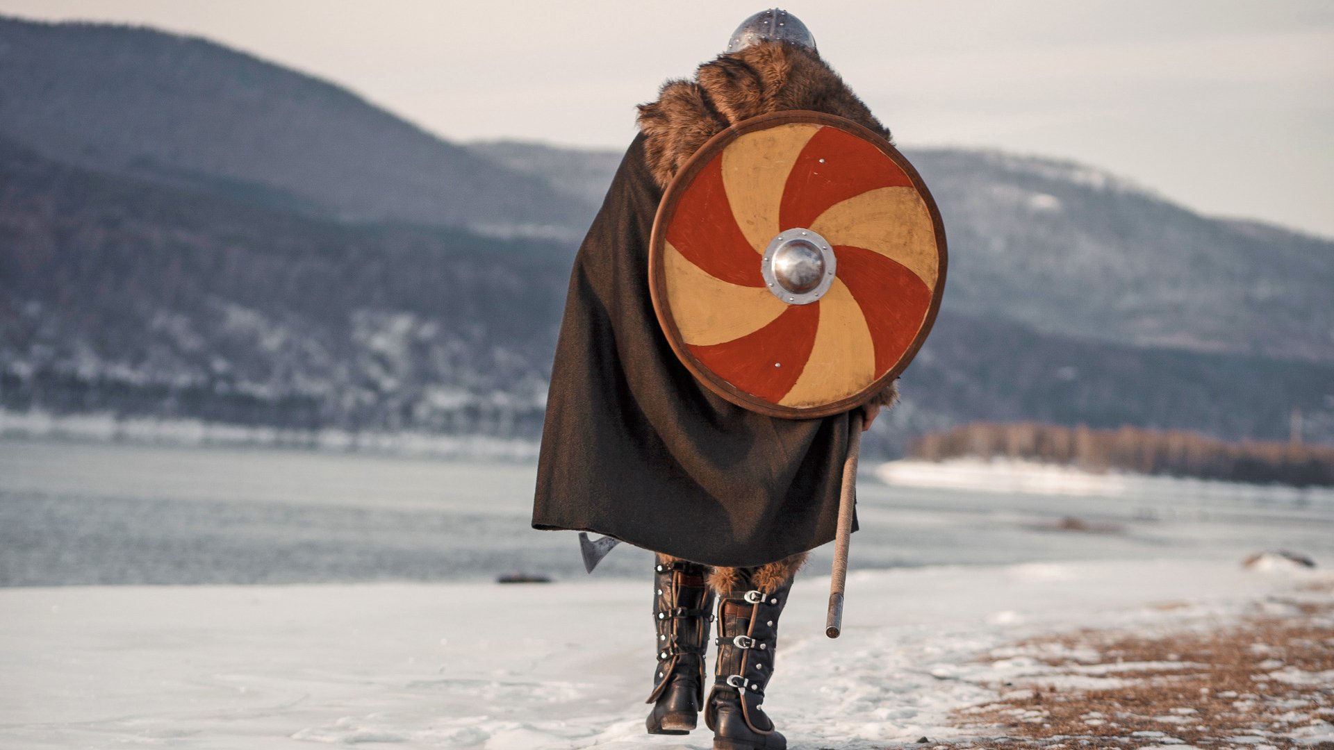 Medieval Scandinavian warrior Viking in full outfit on shore of winter sea