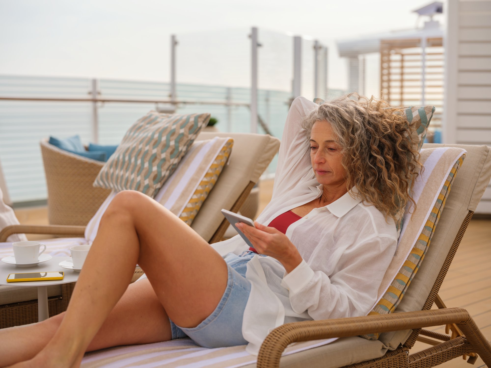 Frau entspannt auf dem Sonnendeck und bucht eine Anwendung auf dem Tablet